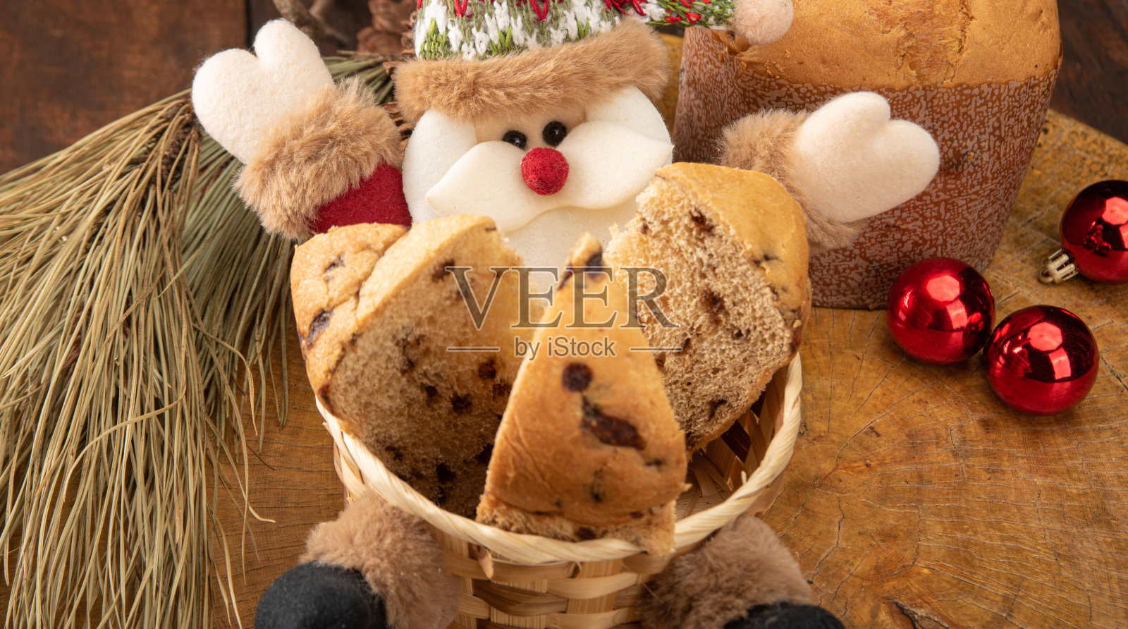 切成薄片的潘妮托妮放在圣诞老人的篮子里，圣诞球放在黑色背景的质朴木桌上，选择性聚焦。照片摄影图片