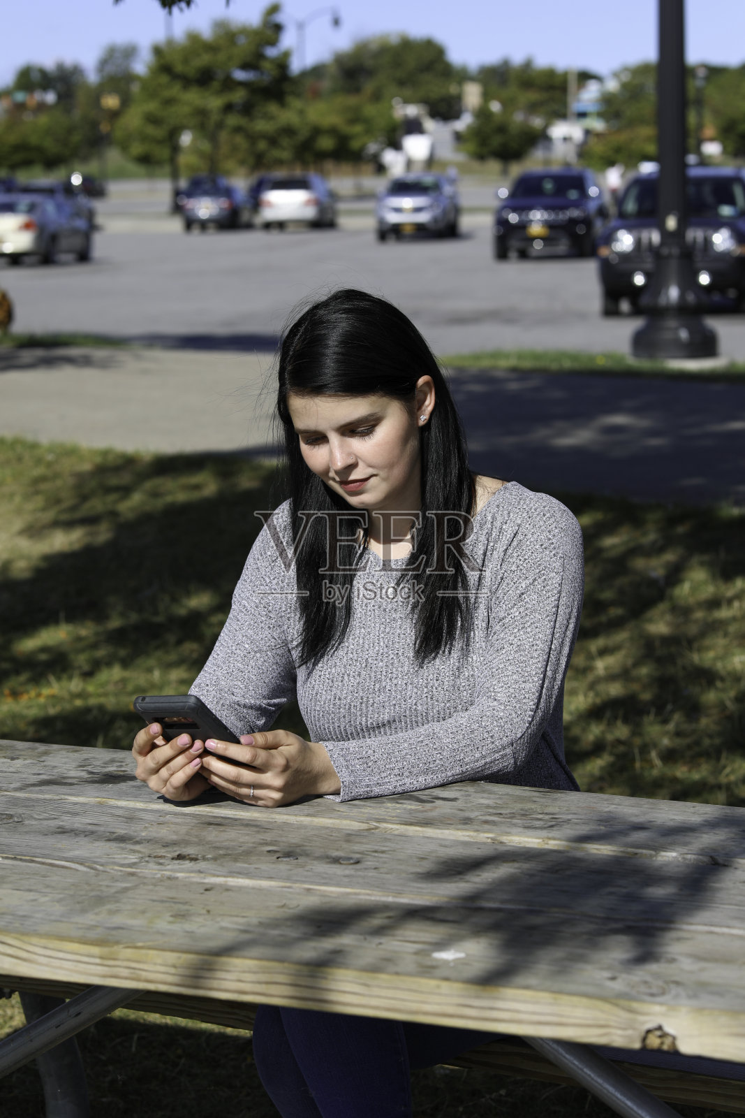 一个年轻女子坐在户外用智能手机查看短信照片摄影图片