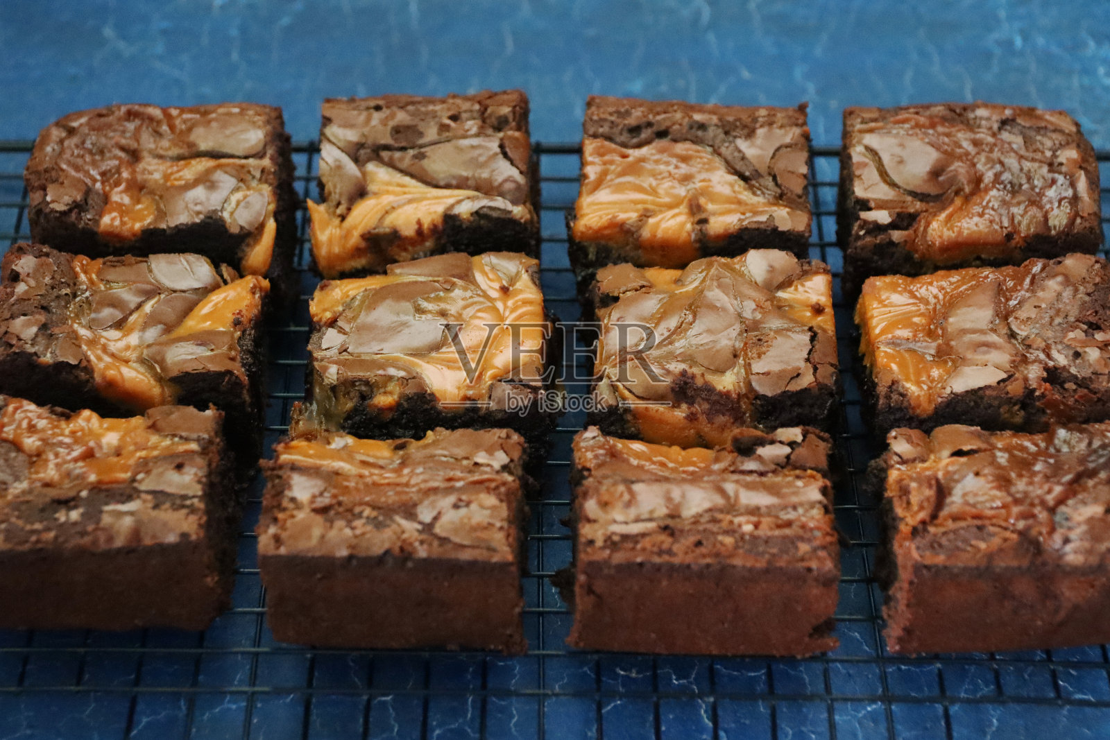 自制巧克力盐焦糖布朗尼方形金属冷却架上的图像，灰色石板背景，高架视野，聚焦前景照片摄影图片