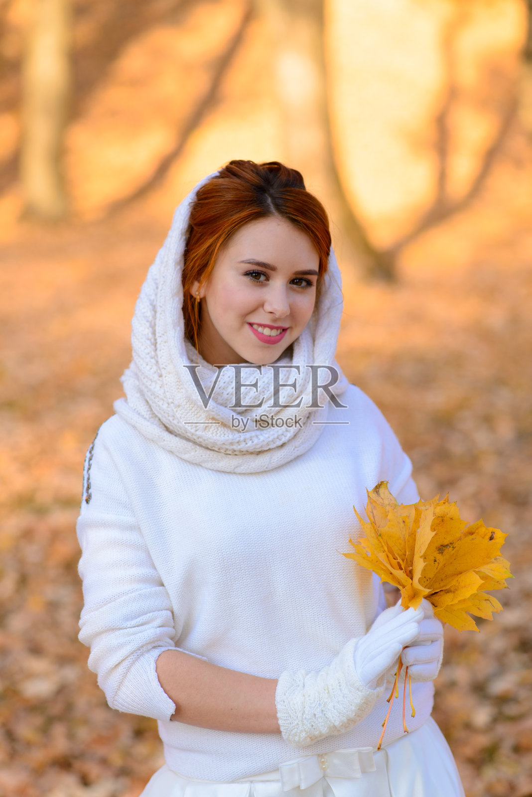 可爱的女孩在长长的白色婚纱摆姿势在秋天的树木在森林在金色的时间气氛乡村小路。照片摄影图片