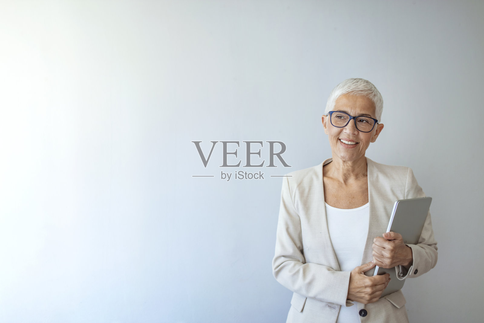 一个在灰色背景下摆姿势的资深妇女的工作室肖像照片摄影图片