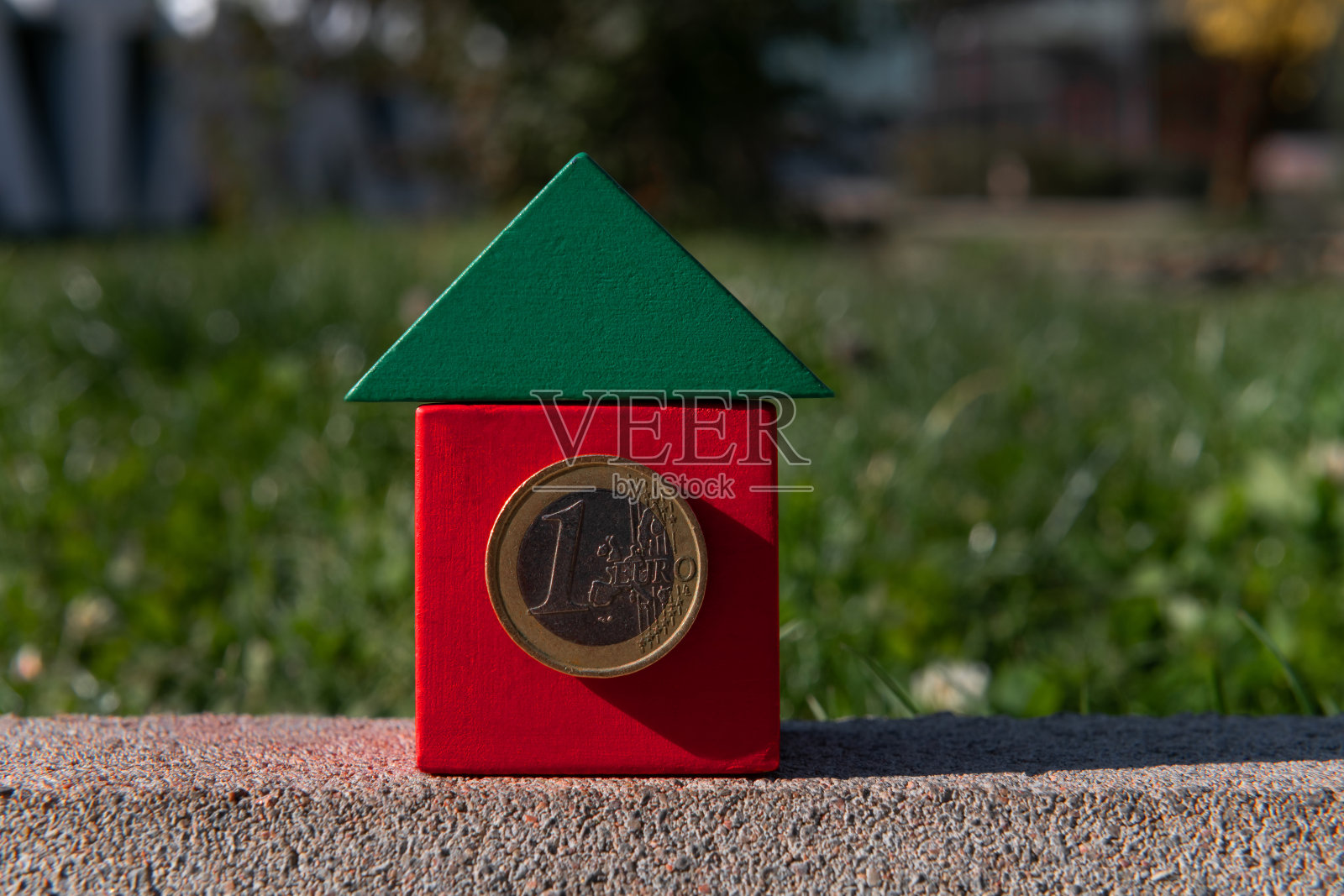 传统的房子由一个立方体和一个三角形组成，用一欧元硬币代替窗户。照片摄影图片