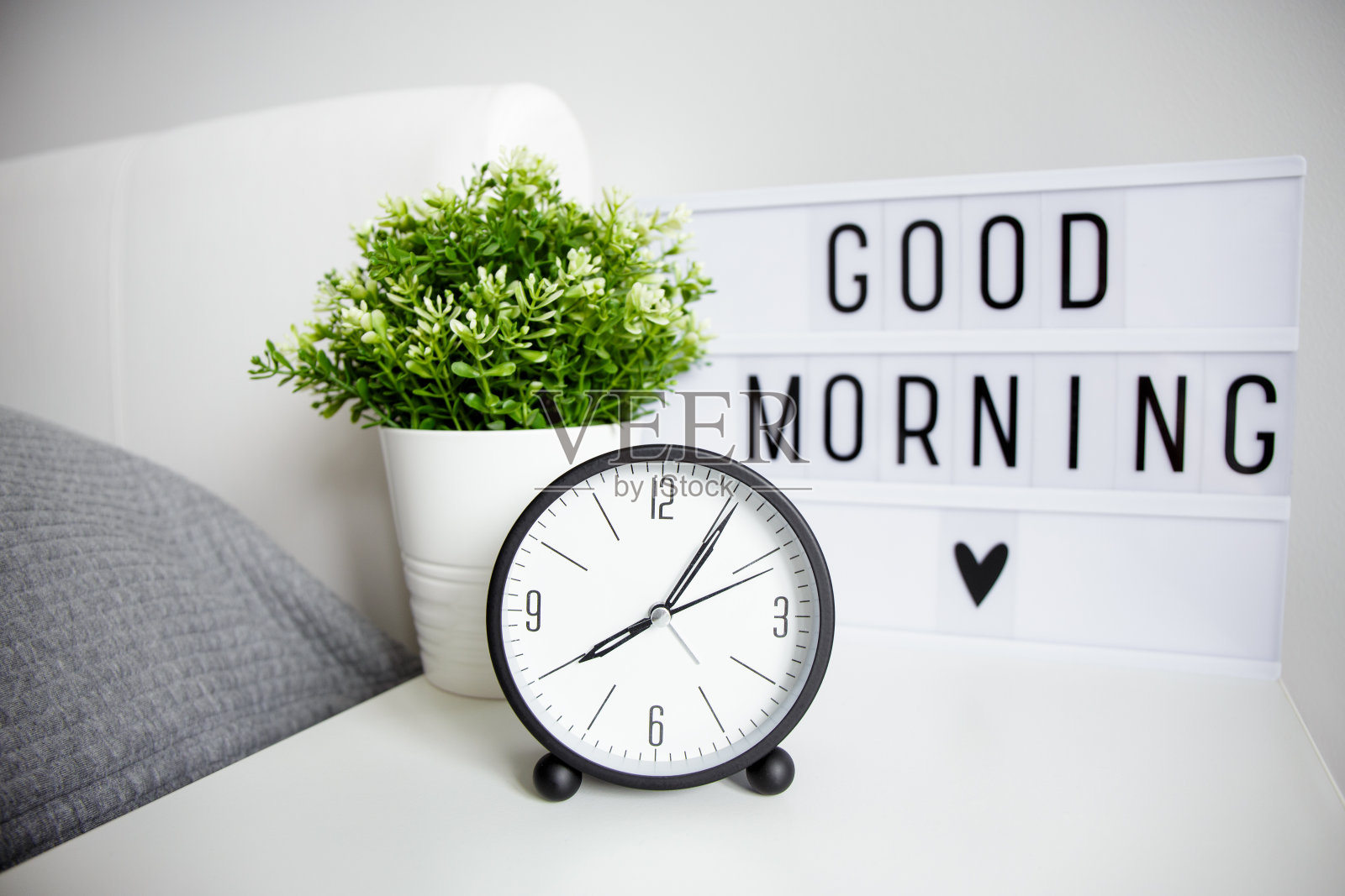 早上好概念-关闭闹钟，室内植物和灯箱与“早上好”的文字在床头柜照片摄影图片