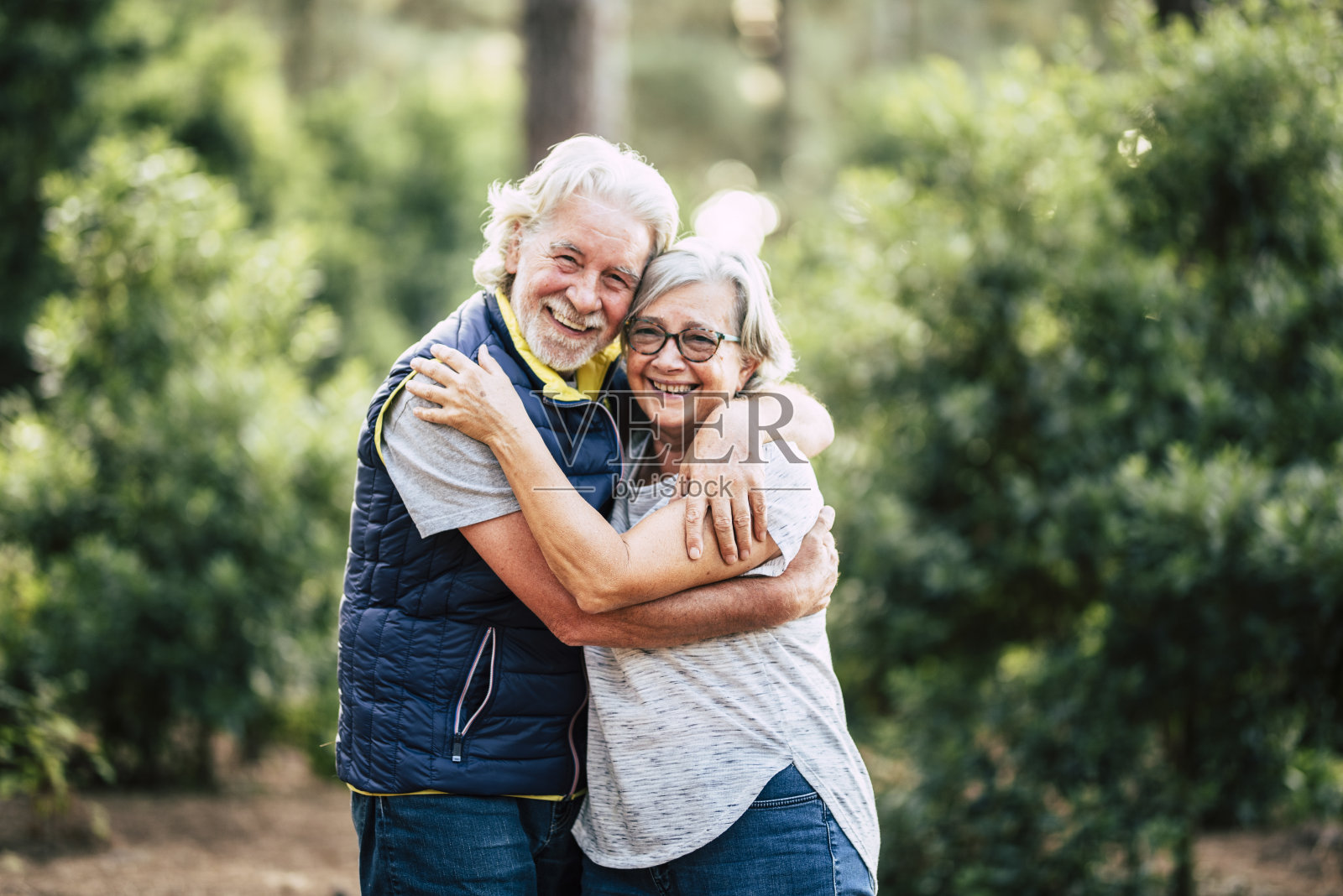 在森林中拥抱并保持爱的老年夫妇，享受户外休闲活动 - 绿色自然背景和快乐的老年人在一起照片摄影图片