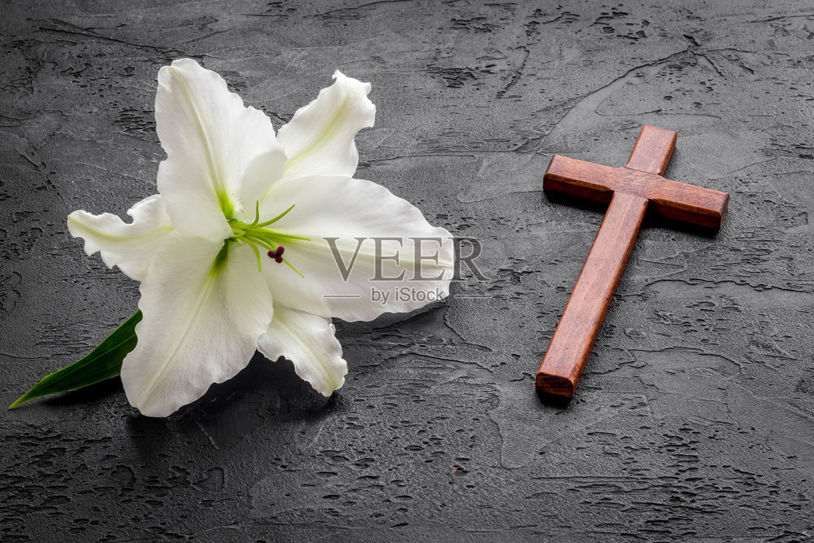 葬礼百合花与十字架上的黑色石头背景。哀悼的象征照片摄影图片