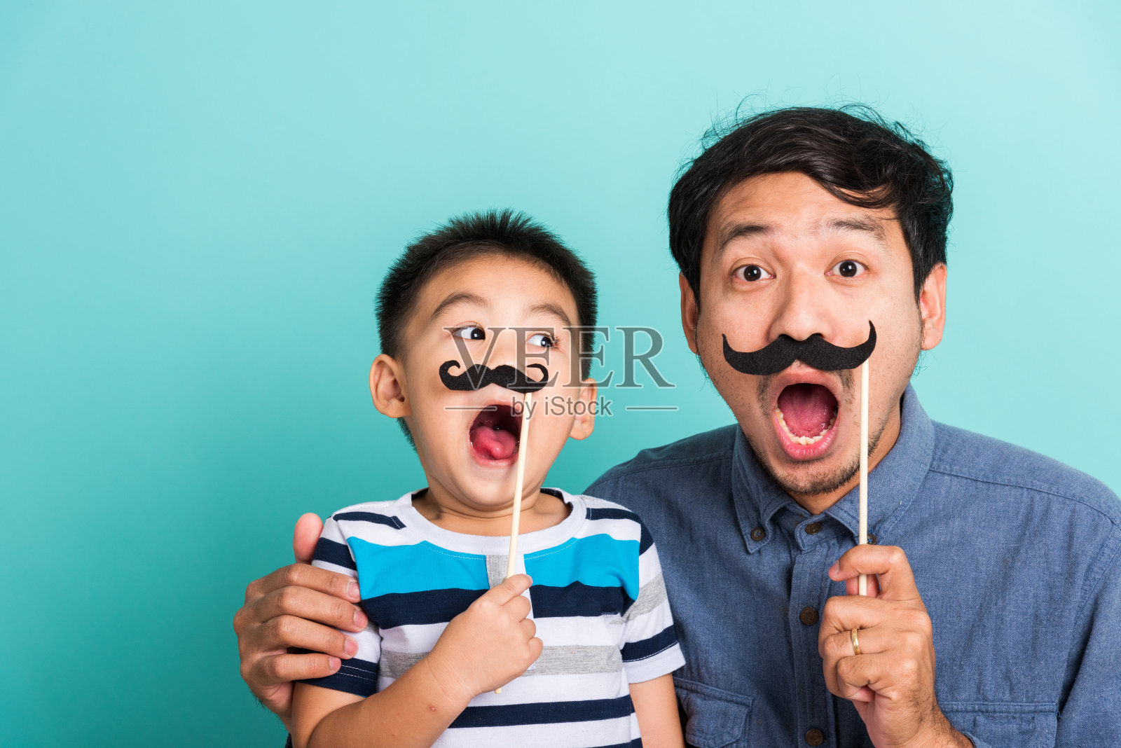 家庭有趣快乐的潮人父亲和他的儿子孩子拿着黑胡子道具照片摄影图片