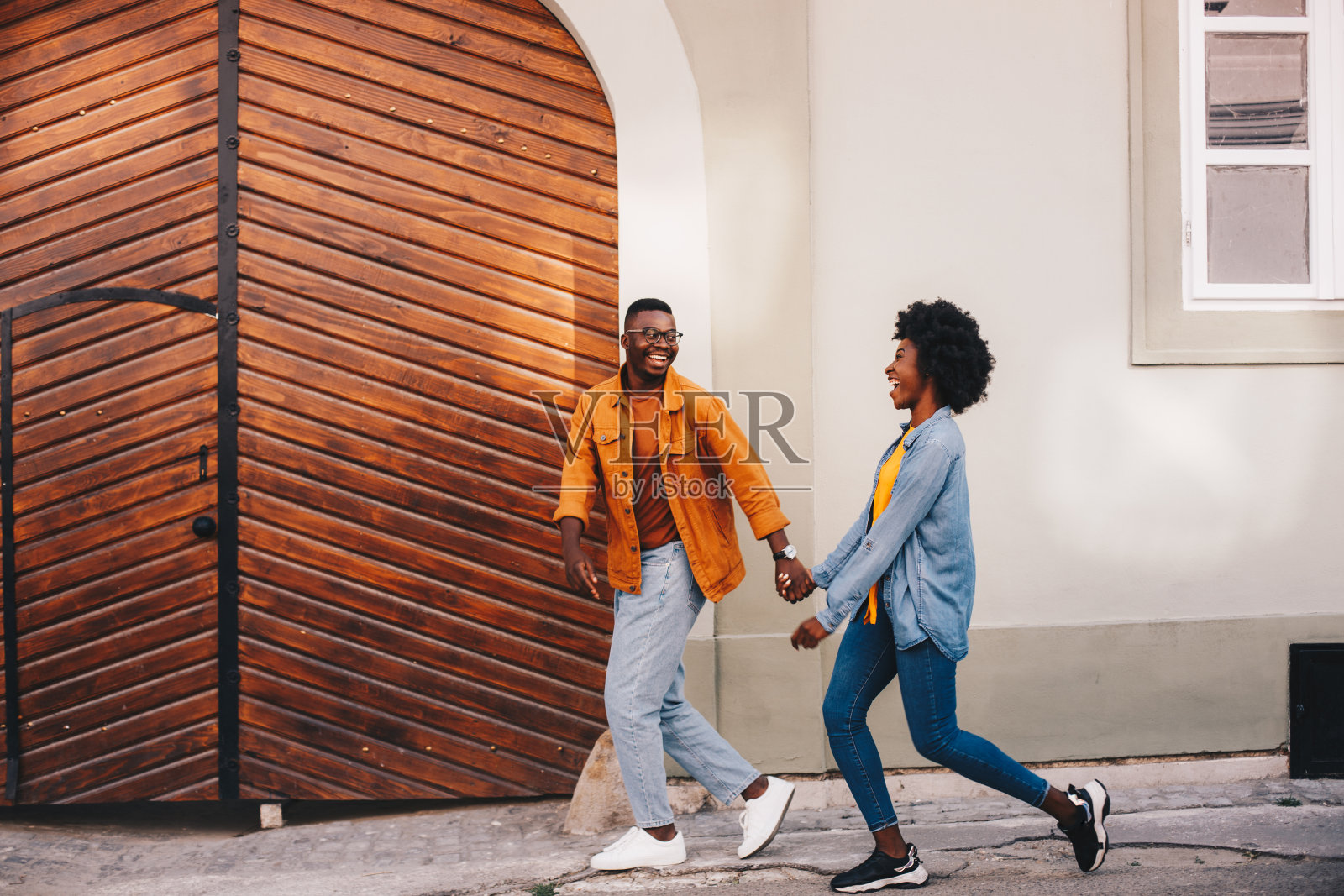 年轻迷人的嬉皮士非洲裔美国夫妇手牵着手走在市中心的街道上。照片摄影图片