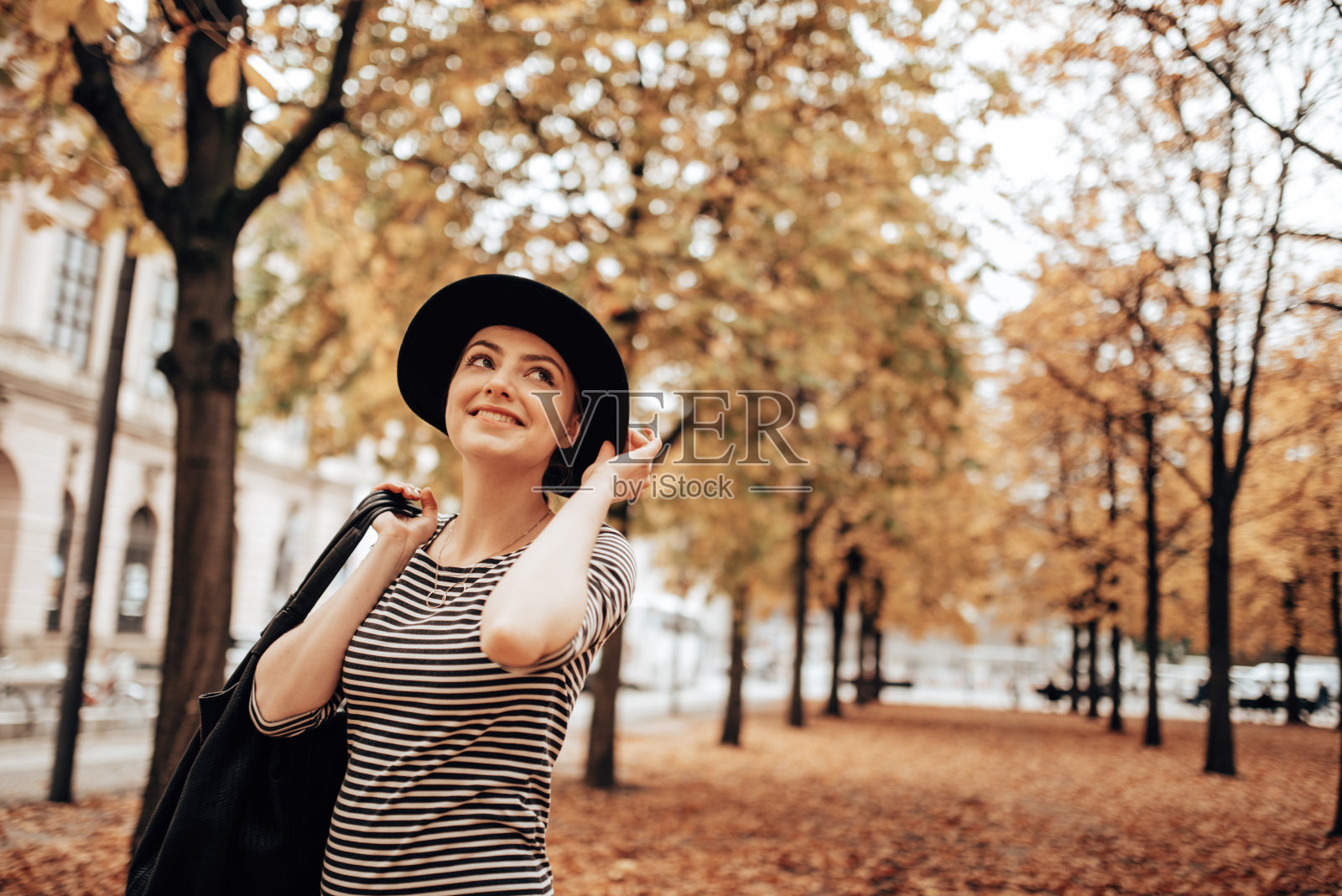 秋天里，时尚的女人在公园里散步照片摄影图片