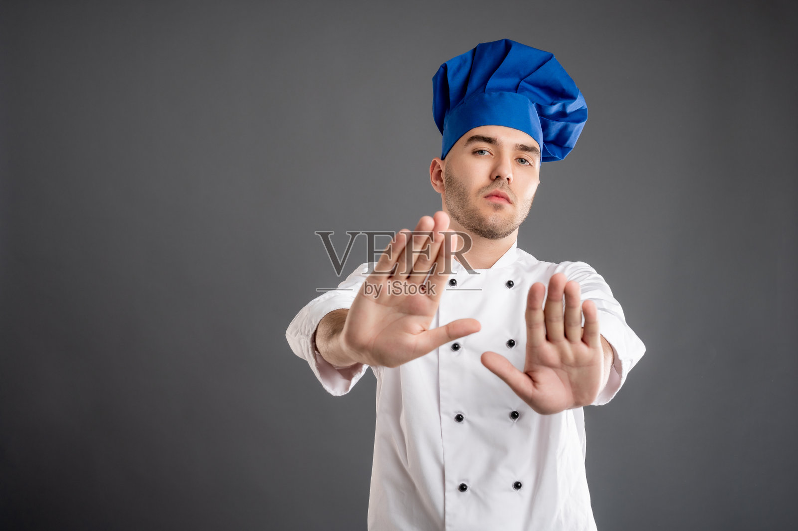 身着白色厨师服的年轻男子双手举着停车标志照片摄影图片