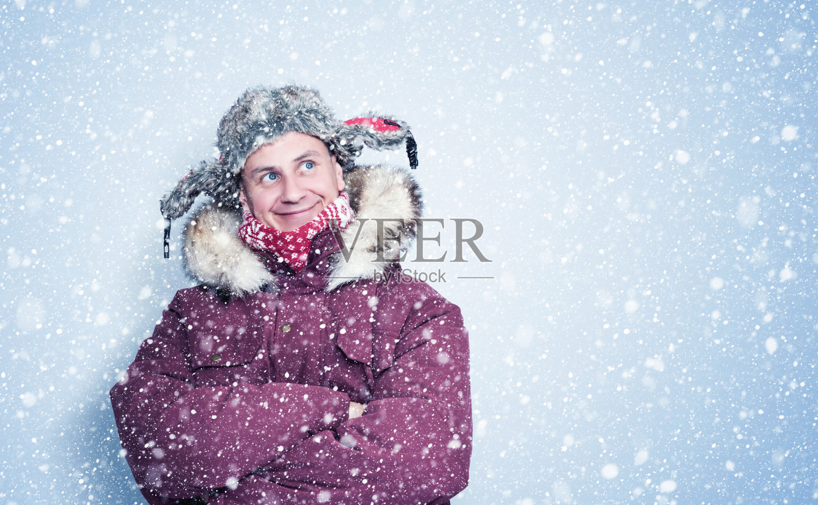 快乐冻人穿着红色冬衣站在墙边，雪花四处飘落照片摄影图片