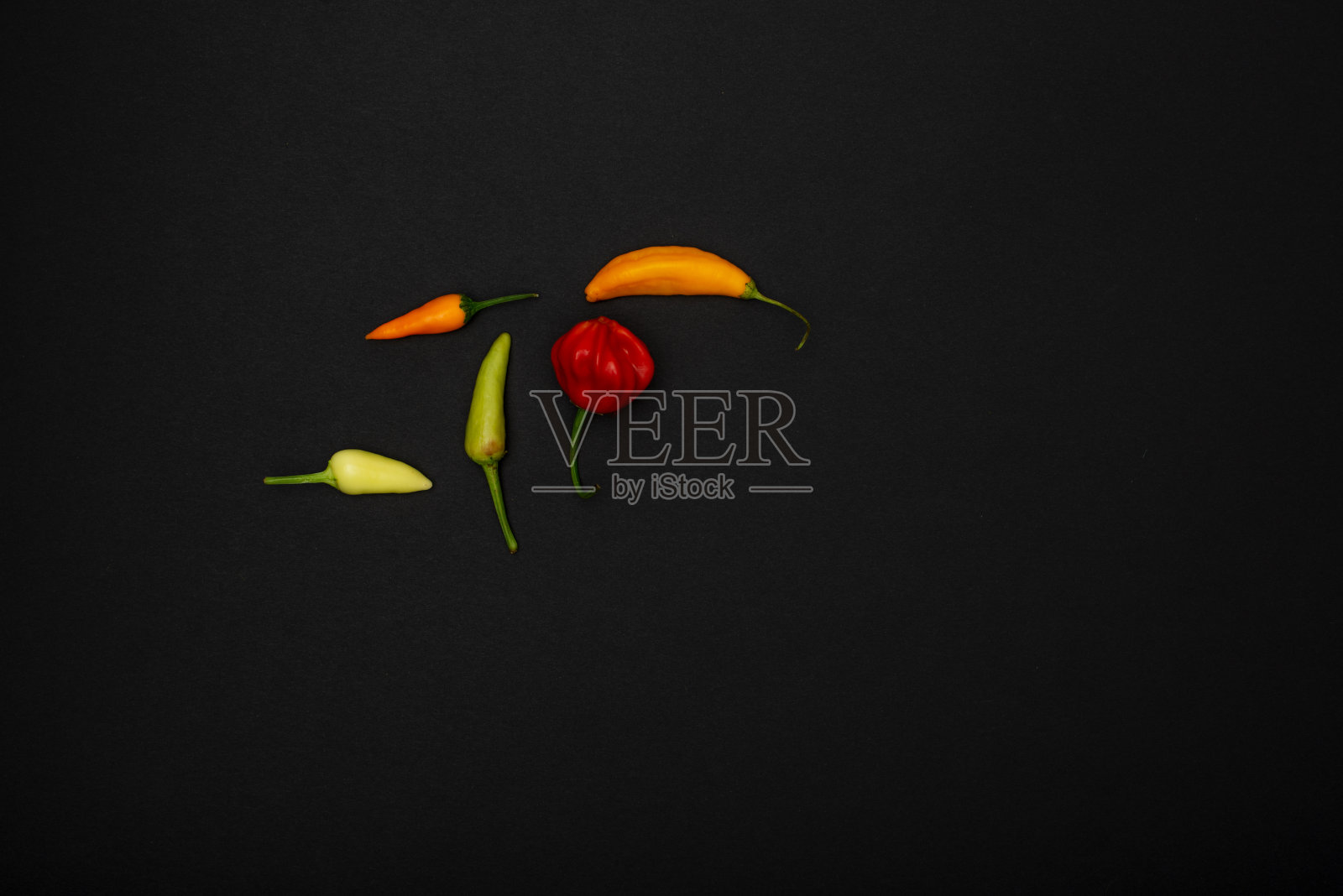 黑色的盘子上放着五颜六色的辣椒照片摄影图片