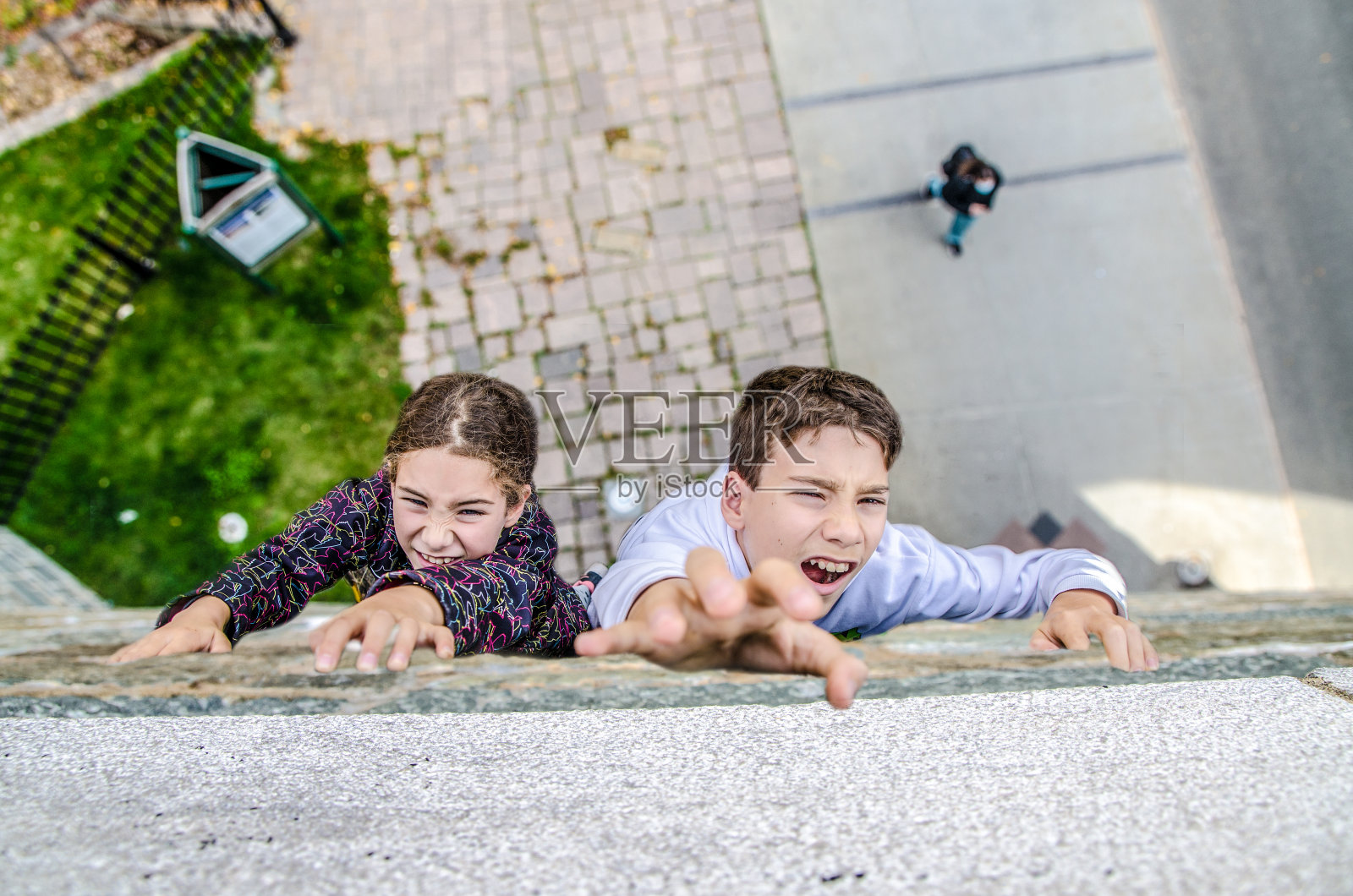 两个孩子在爬一堵很高的水泥墙照片摄影图片