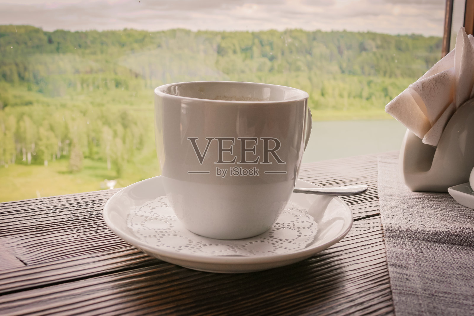 在咖啡馆的桌子上放着一杯咖啡和一个茶托。大自然的全景。照片摄影图片