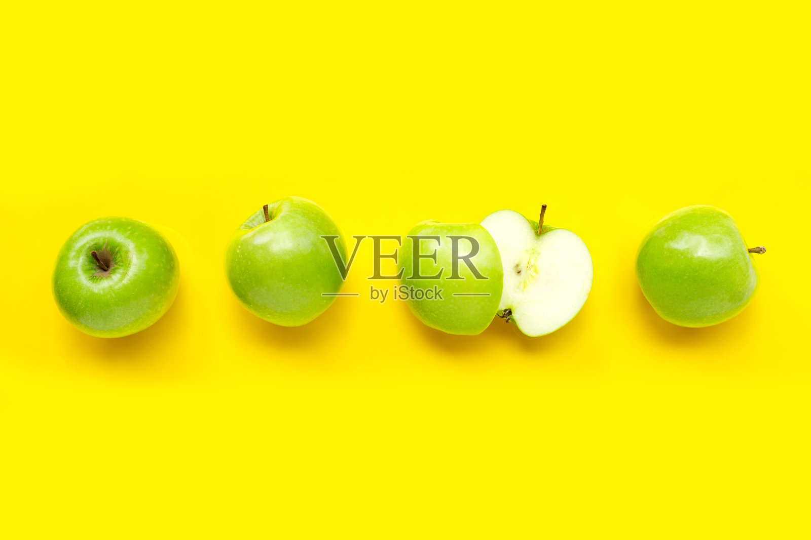 黄色背景上的绿苹果。照片摄影图片