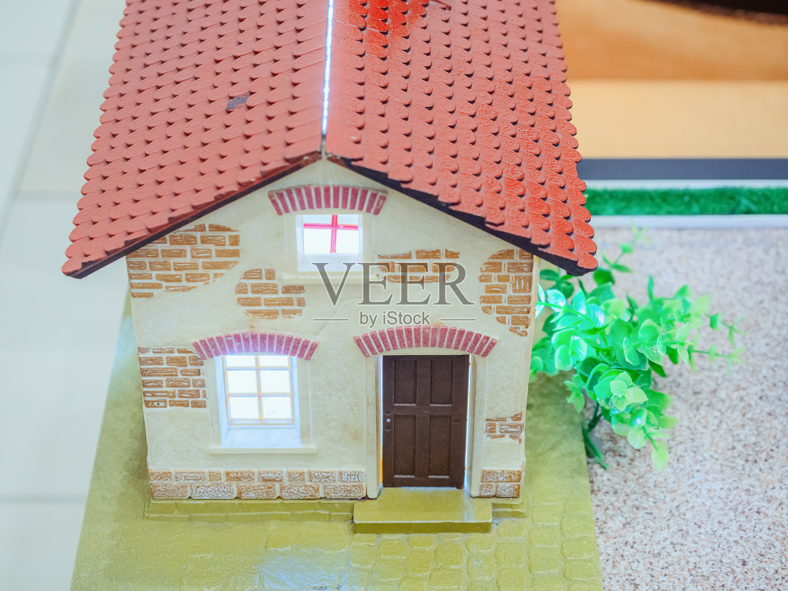 有窗、门和红屋顶的微型房子，附近有绿色的灌木丛照片摄影图片