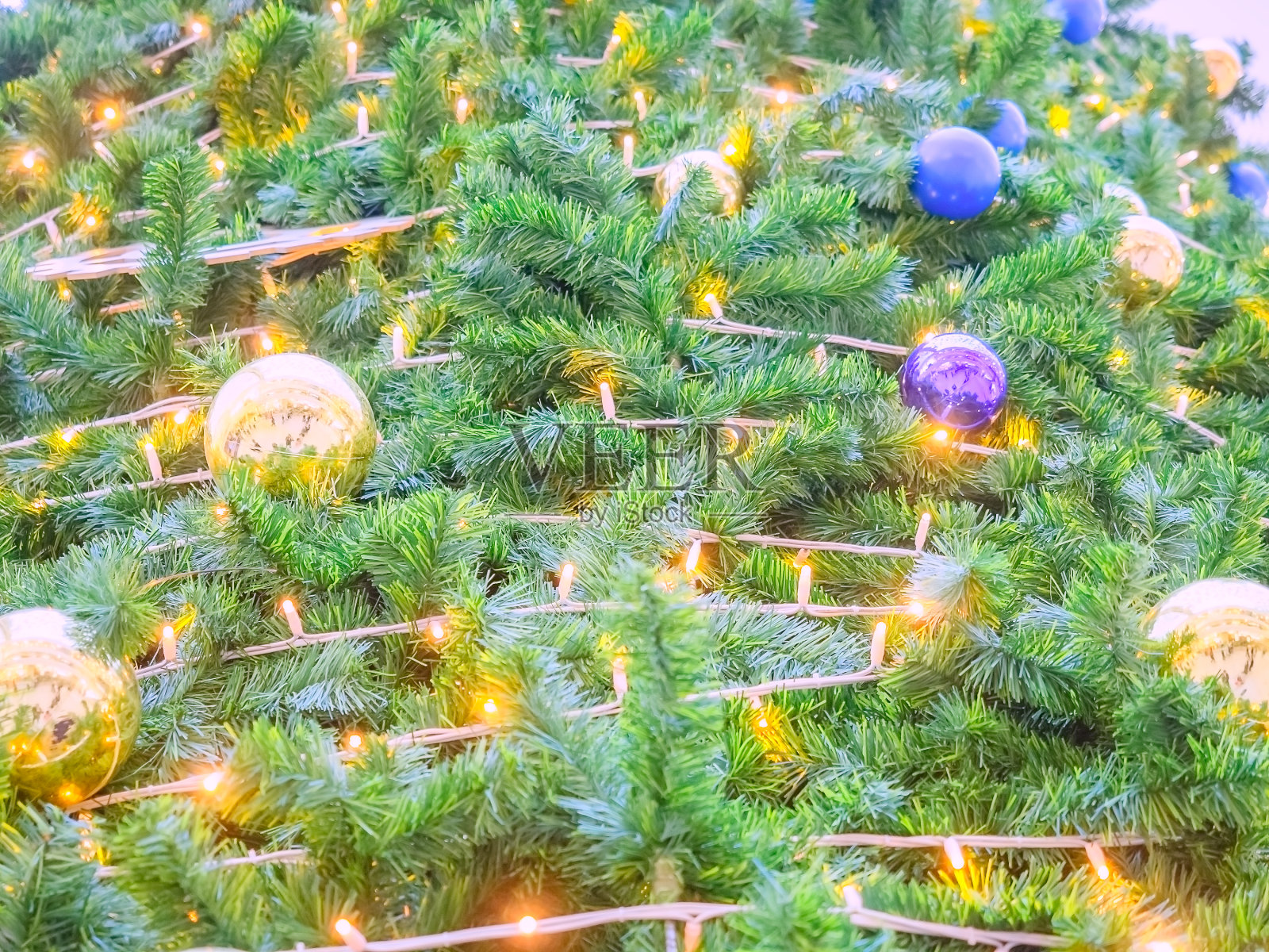 一棵枝繁叶茂的圣诞树，上面挂着发光的花环，还有蓝色和金色的球。全屏照片照片摄影图片