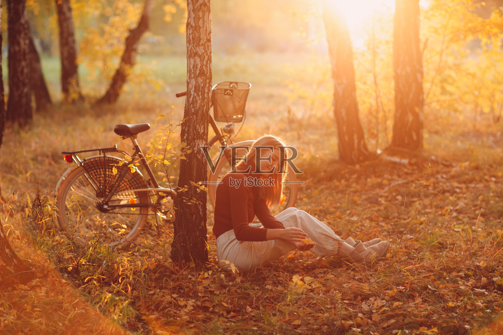 快乐活跃的年轻女子坐在复古自行车在秋天公园日落照片摄影图片