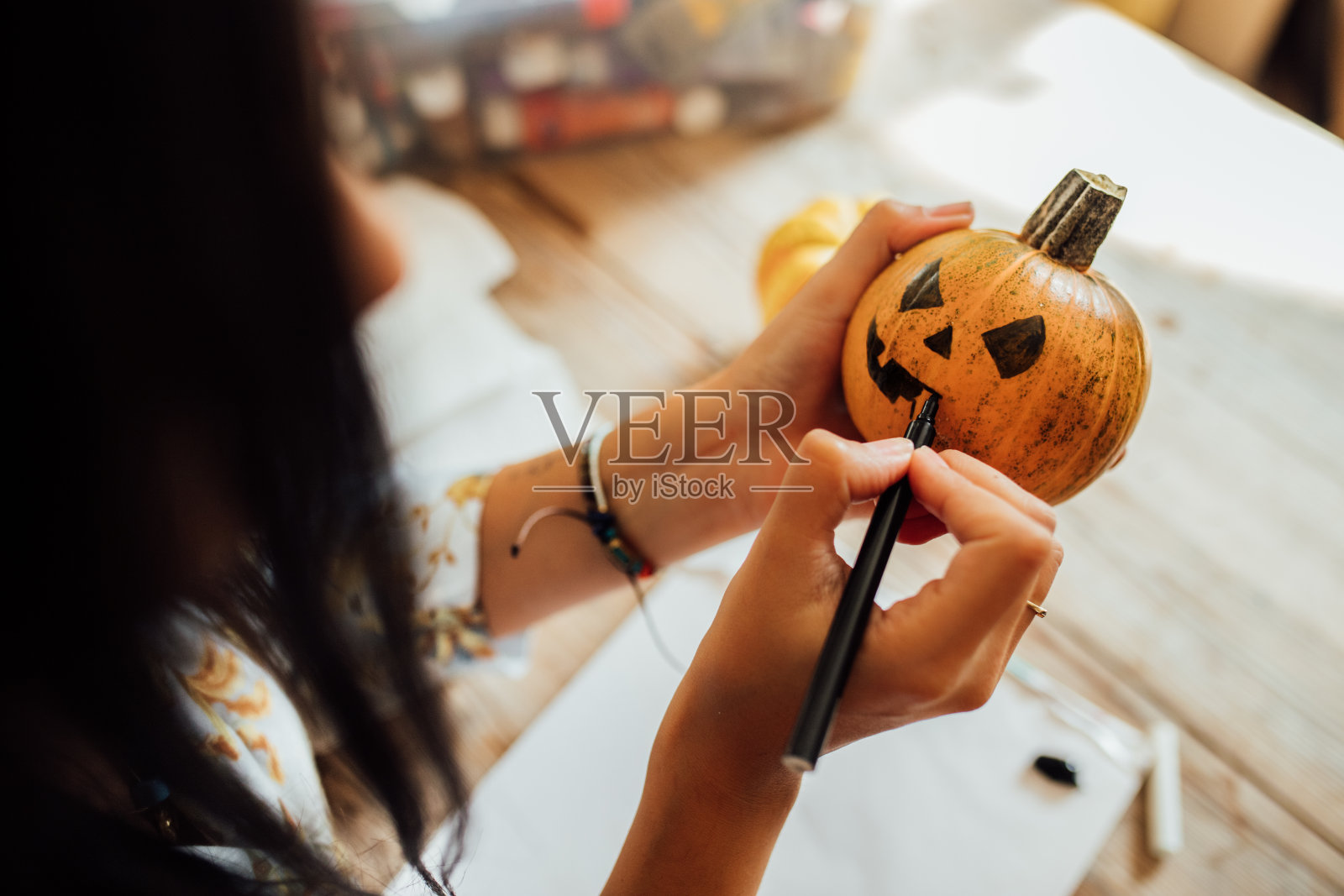 在万圣节南瓜上画鬼脸的女人照片摄影图片