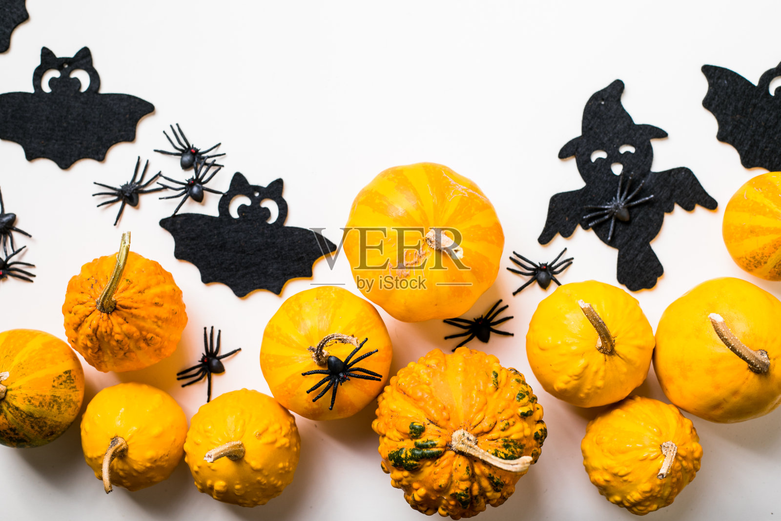万圣节装饰的框架在柔和的白色背景。平铺着橙色的南瓜，吓人的蜘蛛，蝙蝠，昆虫。顶部视图与复制空间。节日贺卡模型。照片摄影图片