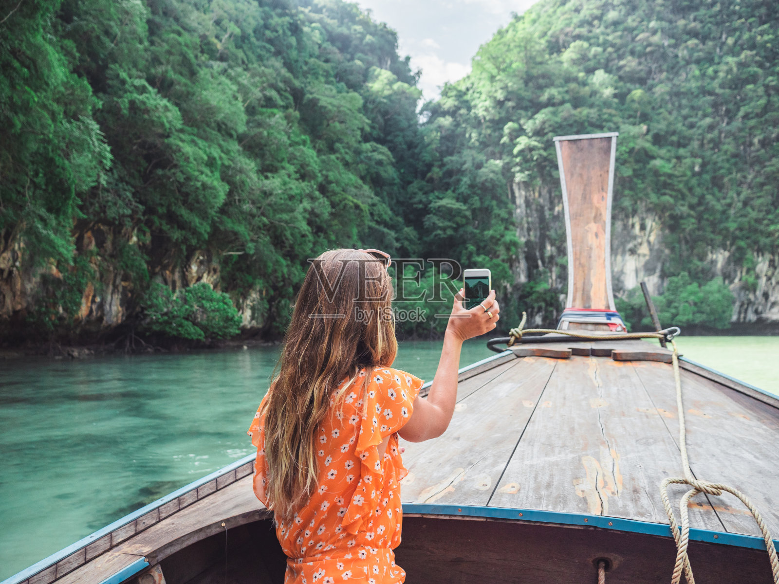 年轻女子在长尾船上用手机拍照照片摄影图片