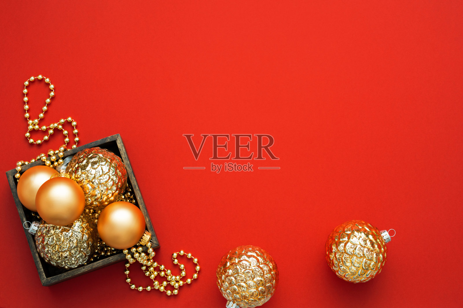 圣诞节deс演说集。不同形状的黄金饰品和珠子放在红色背景的木盒里，并留有复制空间。照片摄影图片