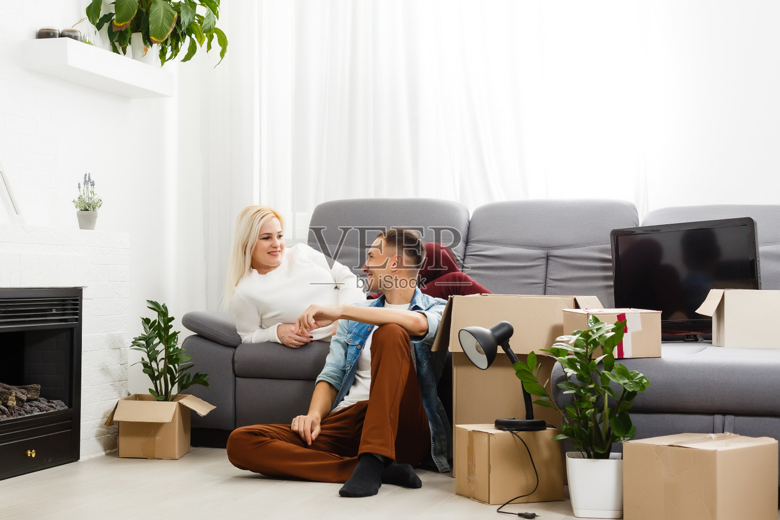 一对年轻夫妇搬着大纸板箱来到新家。移动的房子。照片摄影图片