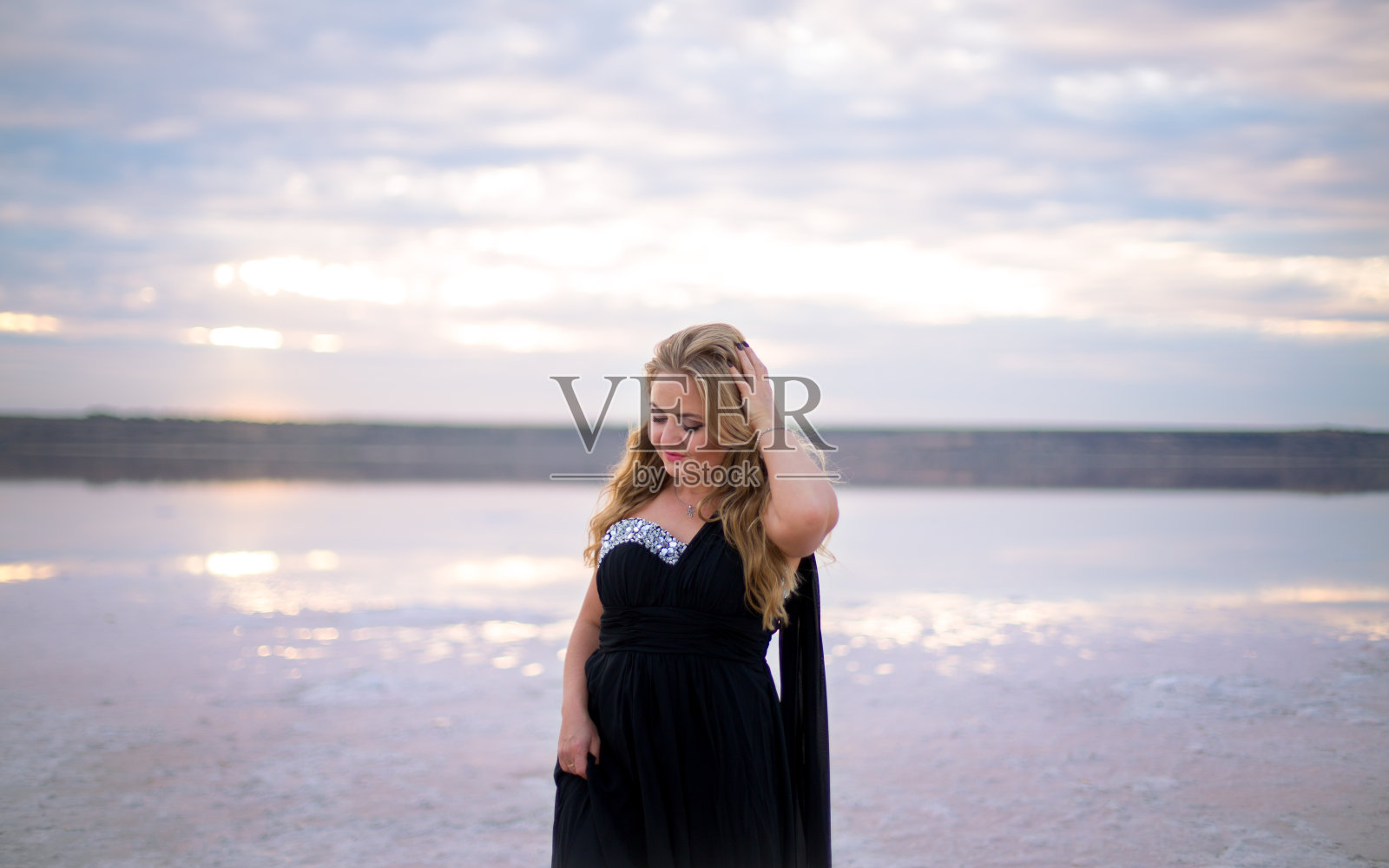 丰满的白人女性在一个咸咸的平静的湖面上的日落黑色裙子照片摄影图片