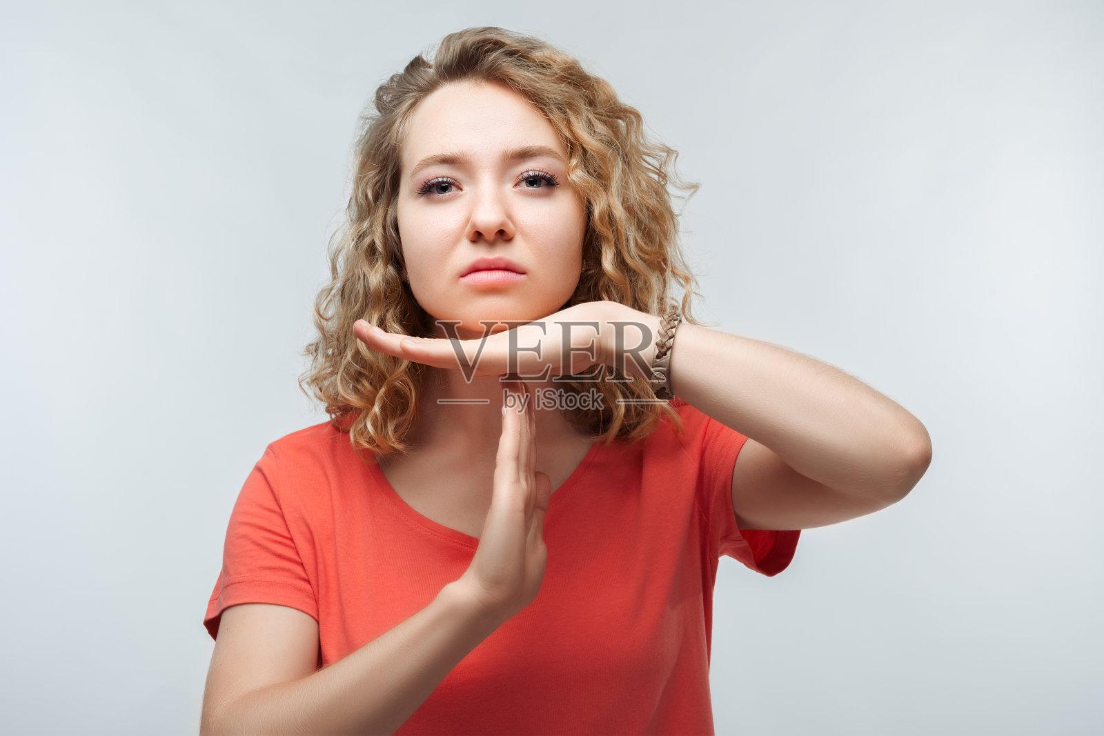 年轻漂亮的金发女人做着暂停的手势。工作室拍摄，白色背景。面部表情的概念照片摄影图片