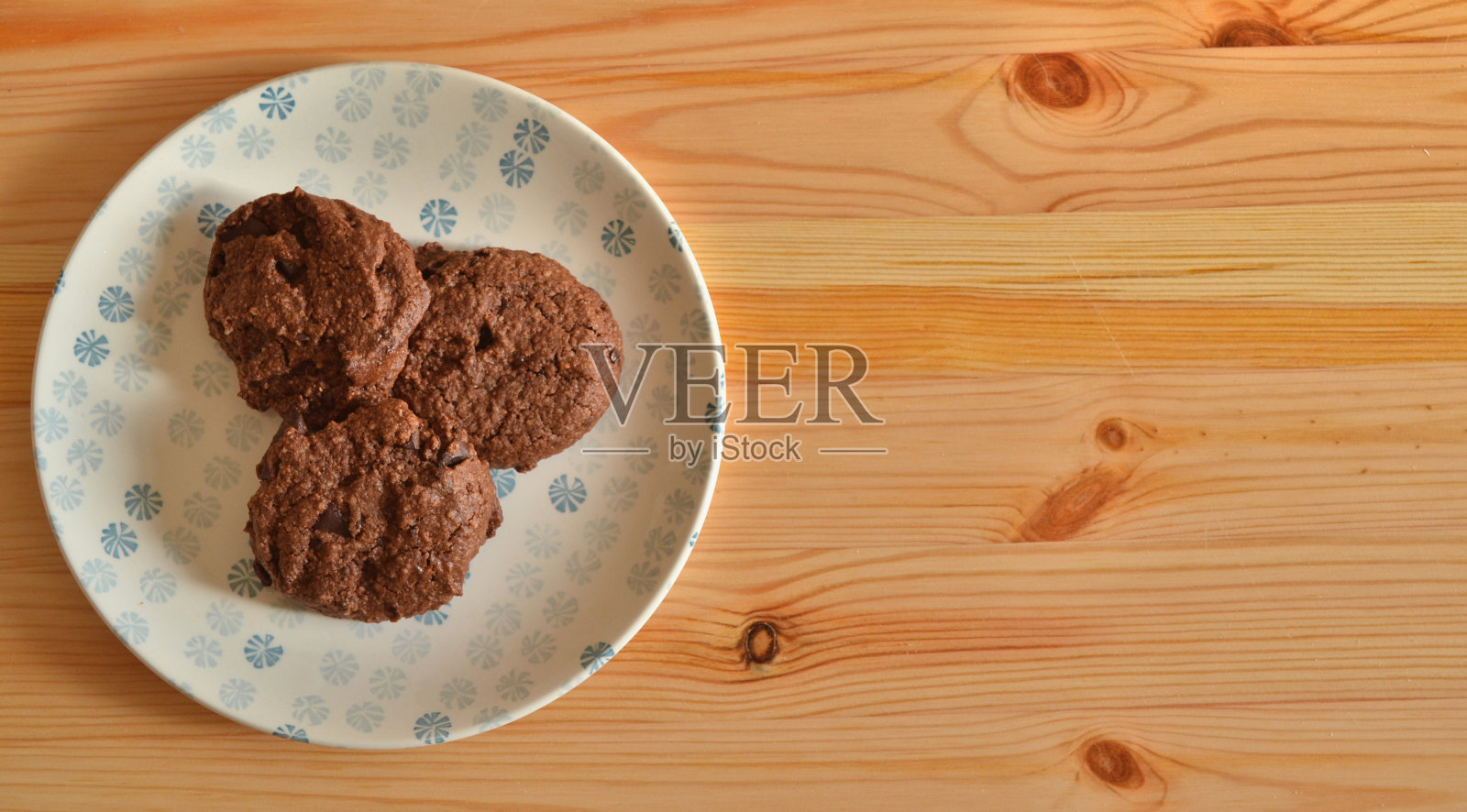 木桌上的瓷盘上放着黑巧克力饼干照片摄影图片
