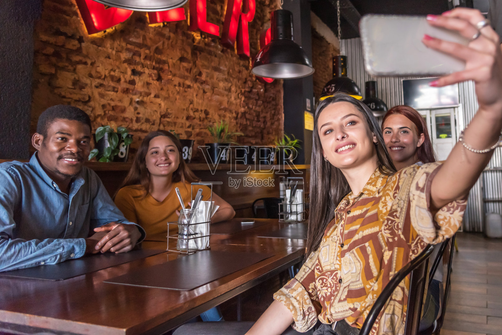 一个漂亮的年轻女子在一家餐馆里与四个朋友一起自拍照片摄影图片