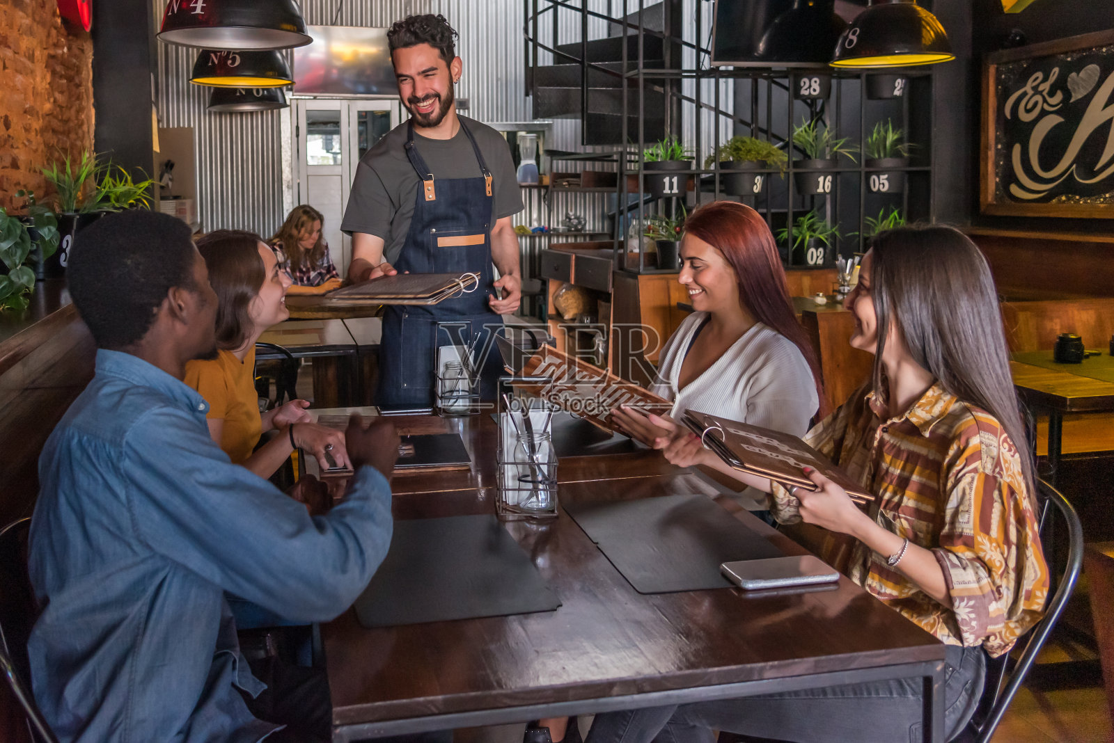 在一家餐馆里，服务员给四个朋友递菜单照片摄影图片