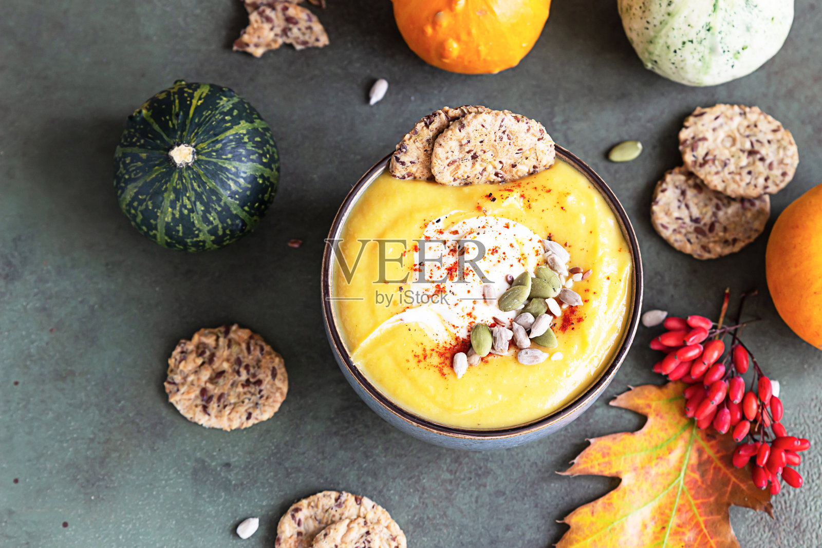 烤浓南瓜素奶油汤与南瓜子，杂粮饼干和种子在绿色的石头背景。前视图。照片摄影图片