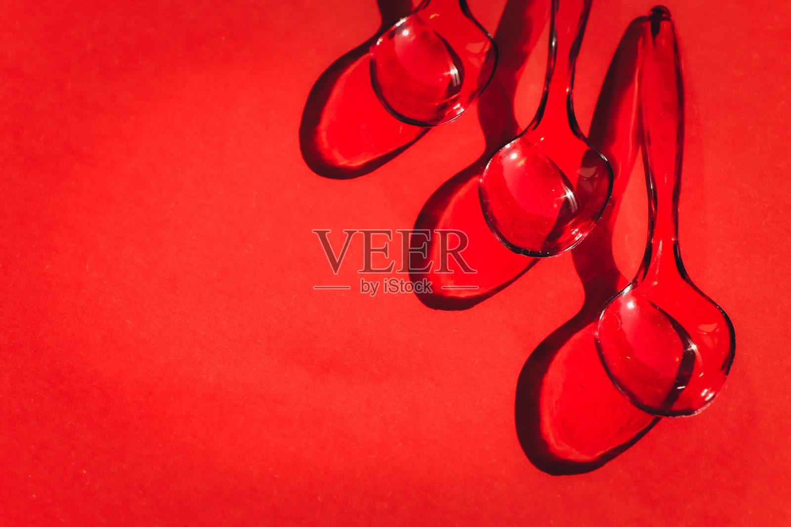 一次性塑料勺，红色背景，对比鲜明的阴影照片摄影图片