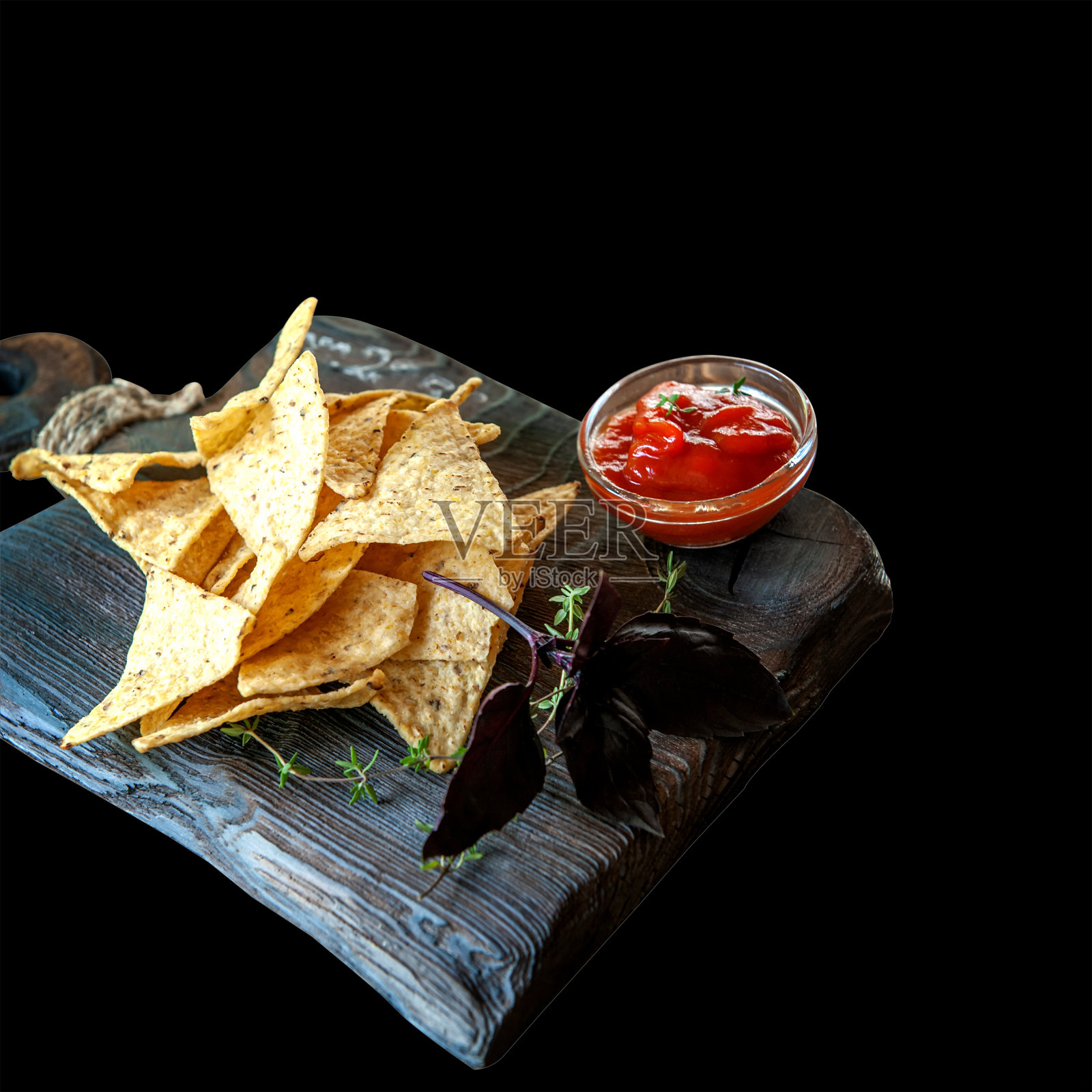 木质背景的烤玉米片，配上罗勒、百里香酱汁和香草。孤立在黑色照片摄影图片