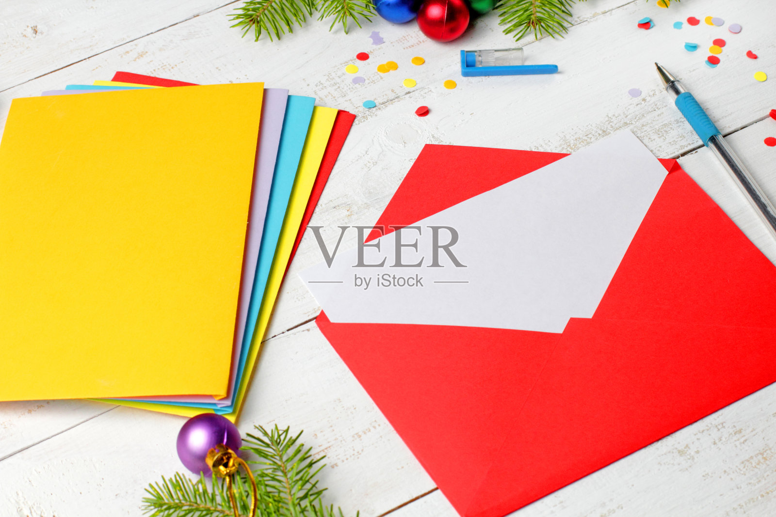 红信封与空白纸，概念圣诞问候或邀请，圣诞树树枝，圣诞球，五彩纸屑。照片摄影图片