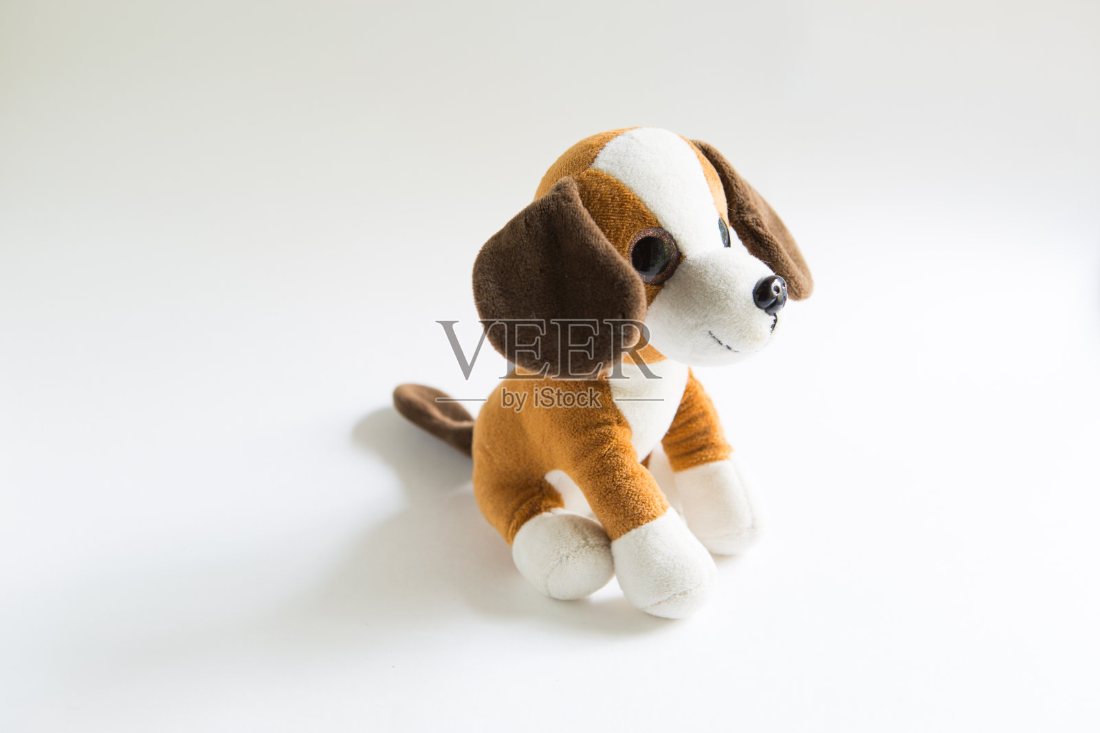 毛绒软软的玩具狗，棕色，白色的口鼻和爪子，黑色的耳朵。照片摄影图片