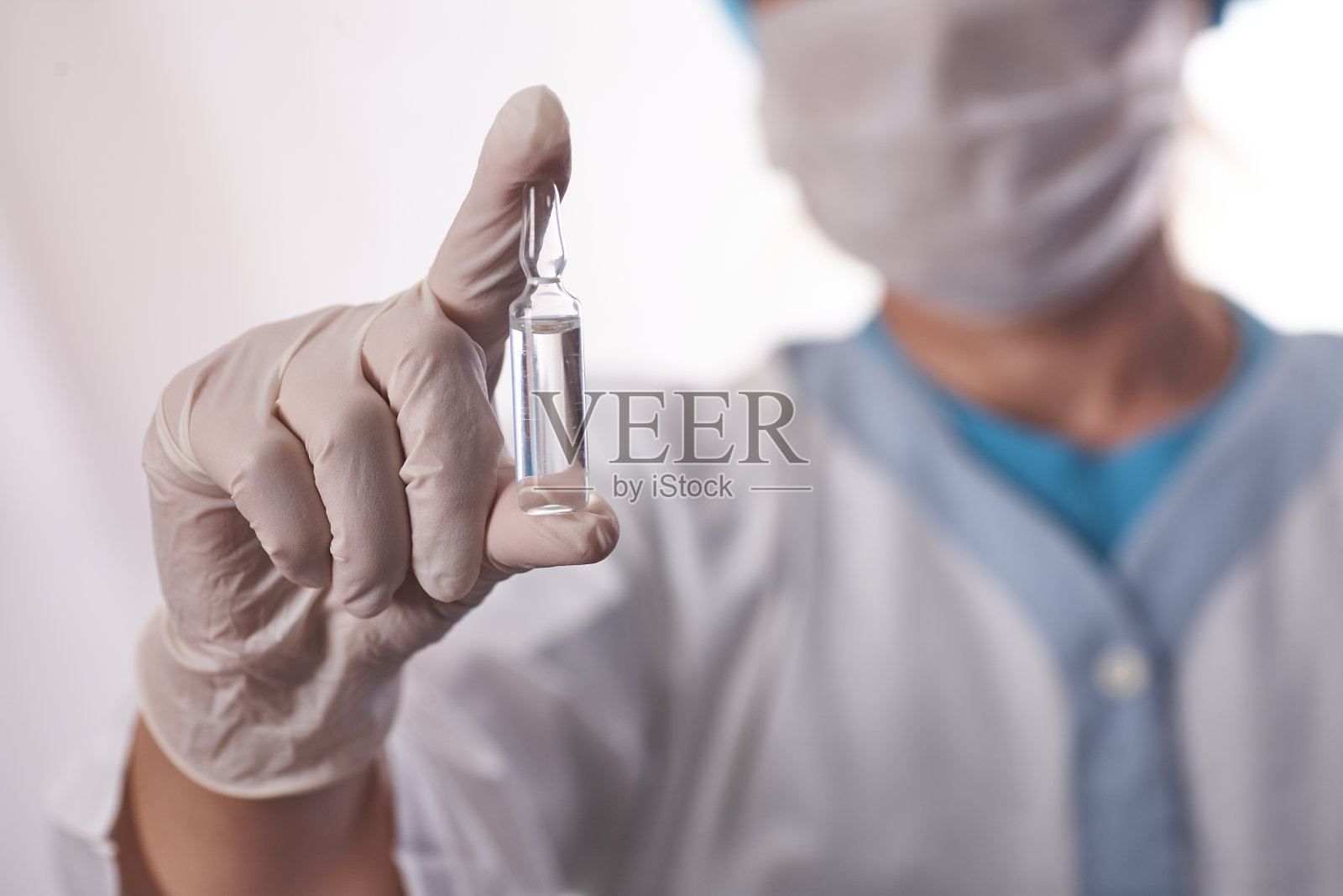 疫苗病毒。冠状病毒的概念。医生手里拿着一支装着疫苗的安瓿，在模糊的蓝色背景上。病毒保护。感冒和流感照片摄影图片