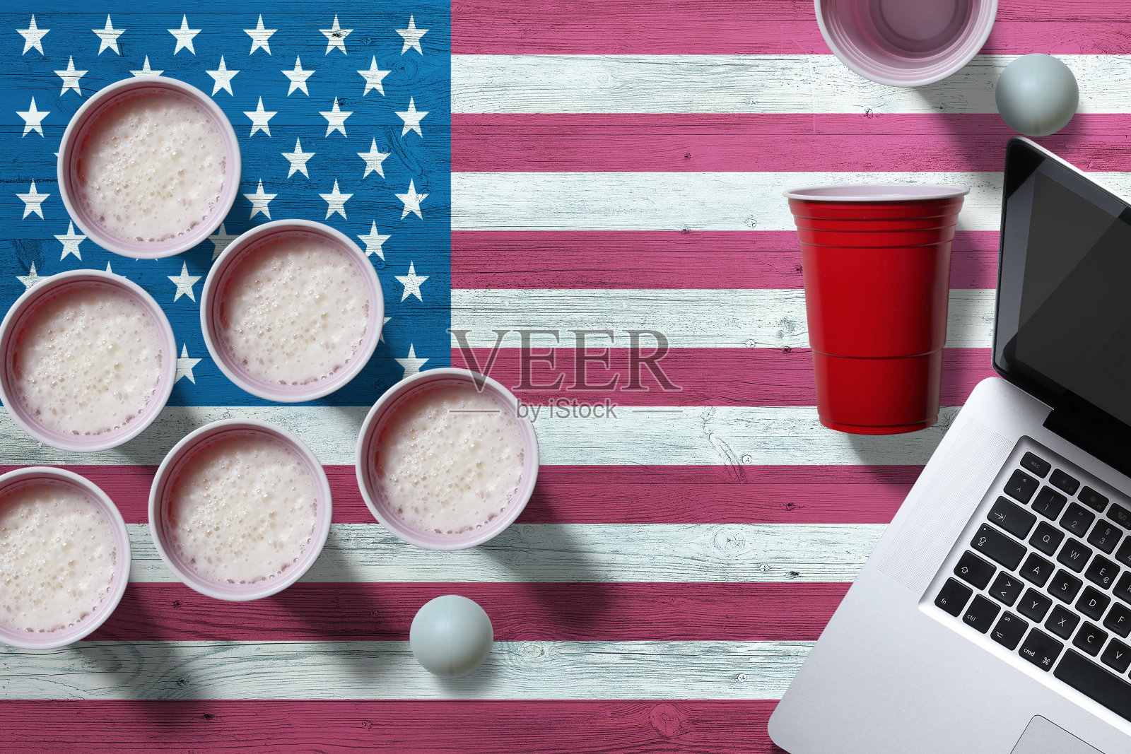 美国国旗概念与塑料啤酒桌球杯和笔记本电脑在国家木桌，俯视图。啤酒乒乓球比赛。照片摄影图片