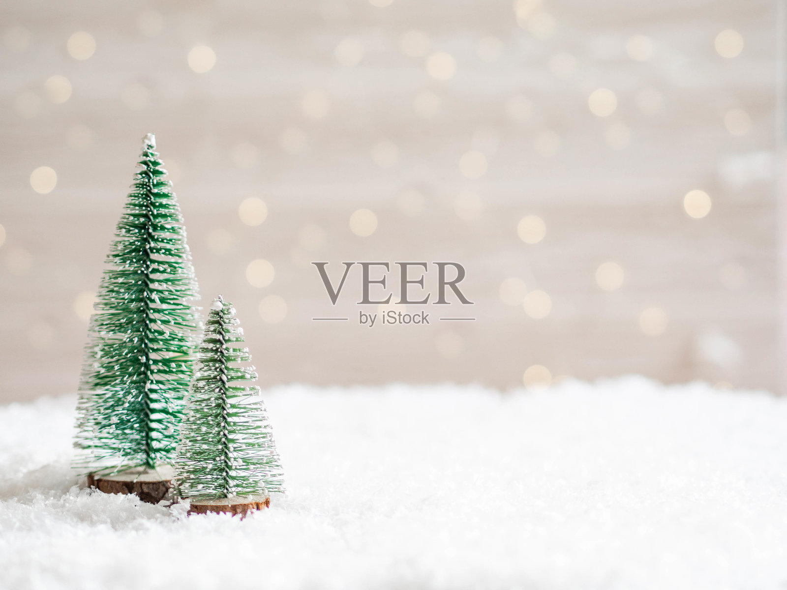 圣诞树在人造雪的前景和模糊的背景与一个发光的花环照片摄影图片