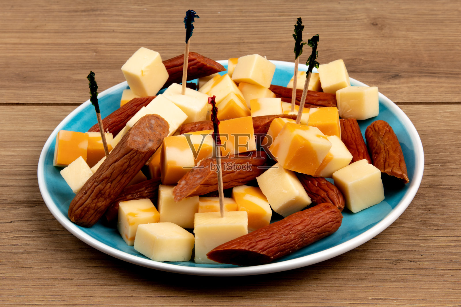 木桌上放着一盘切达干酪块和意大利香肠块照片摄影图片