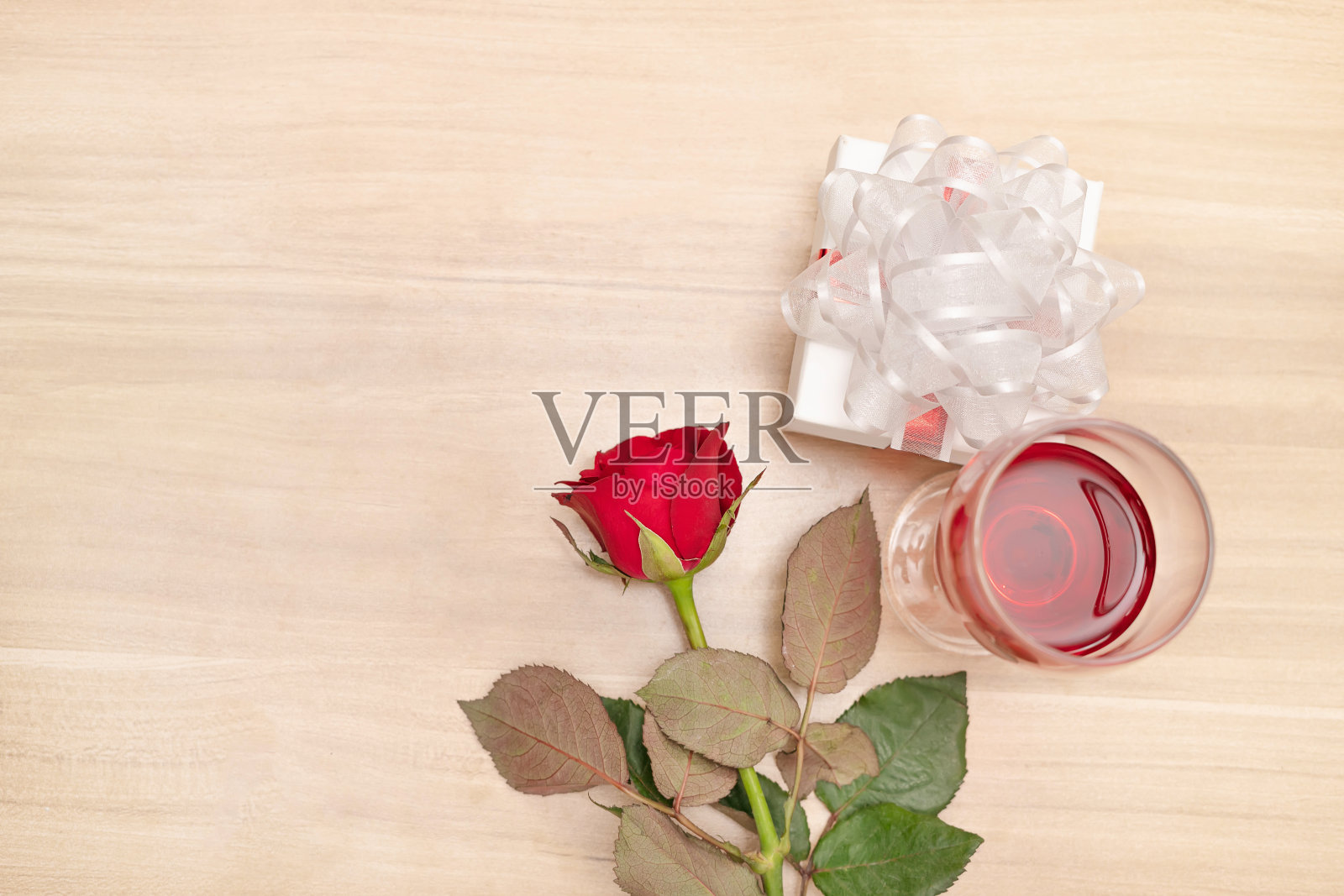 礼物和红玫瑰放在木桌上，配上酒杯，送礼和收到特别的人的礼物是幸福的概念照片摄影图片