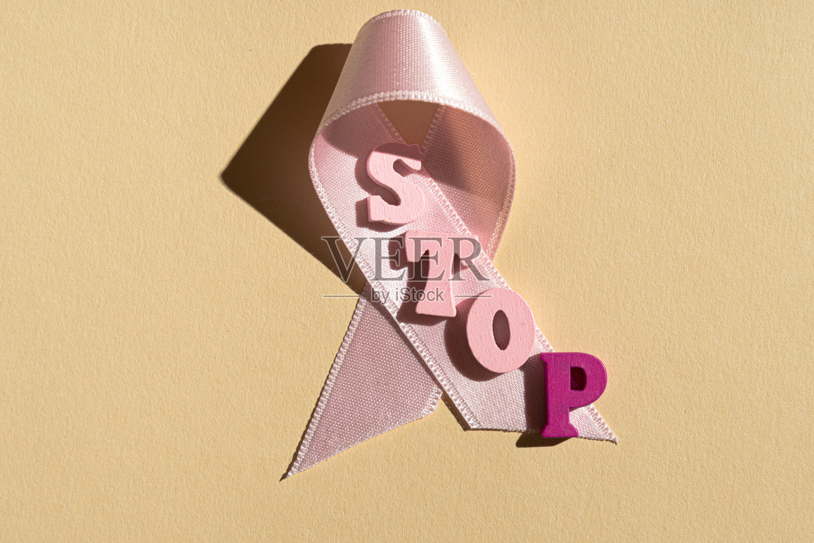 黄色背景上的粉色丝带上的停止字。乳腺癌。照片摄影图片