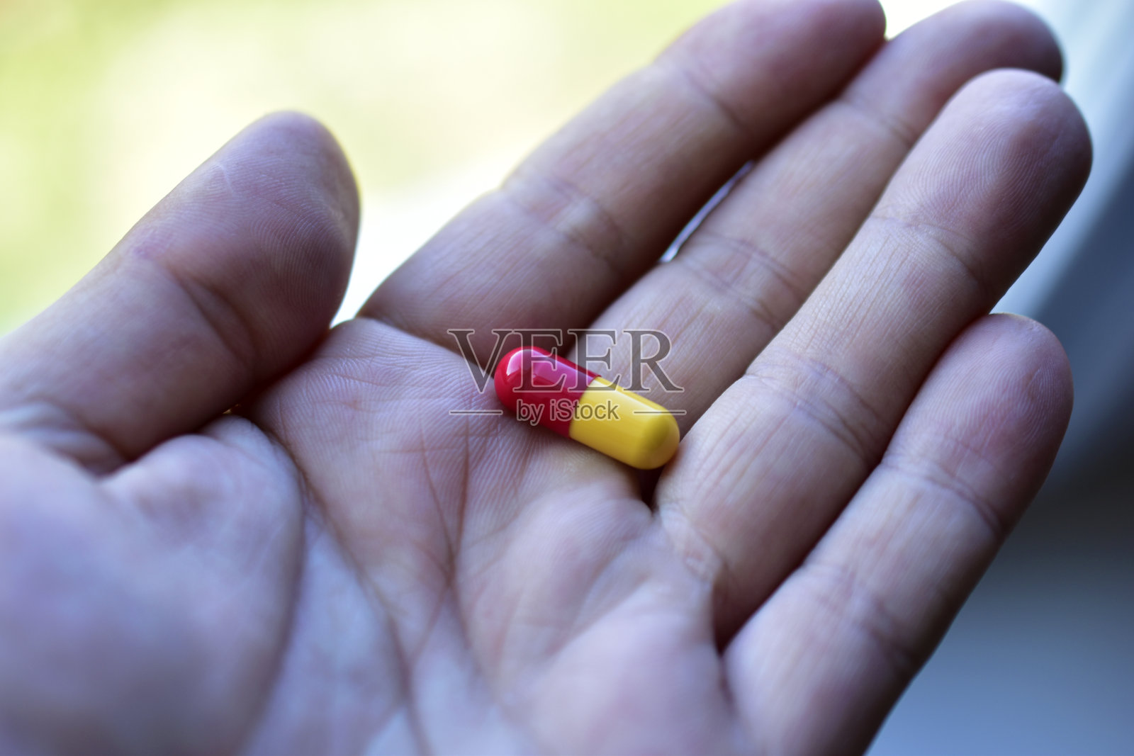 白天手里拿着黄色的红色药丸照片摄影图片