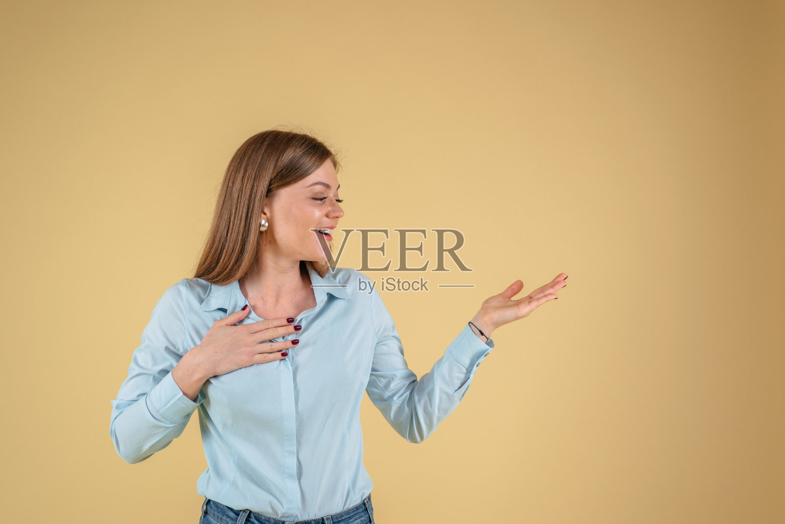 一个漂亮女人的肖像展示一个产品在黄色的背景，空白照片摄影图片