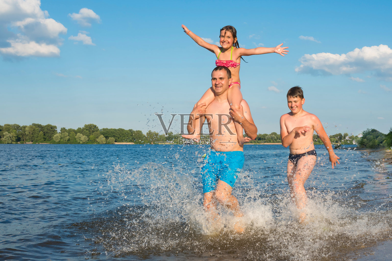 幸福的家庭在海滩上玩，在日落时在水里跑步和跳跃。度假、体育、生活方式。照片摄影图片