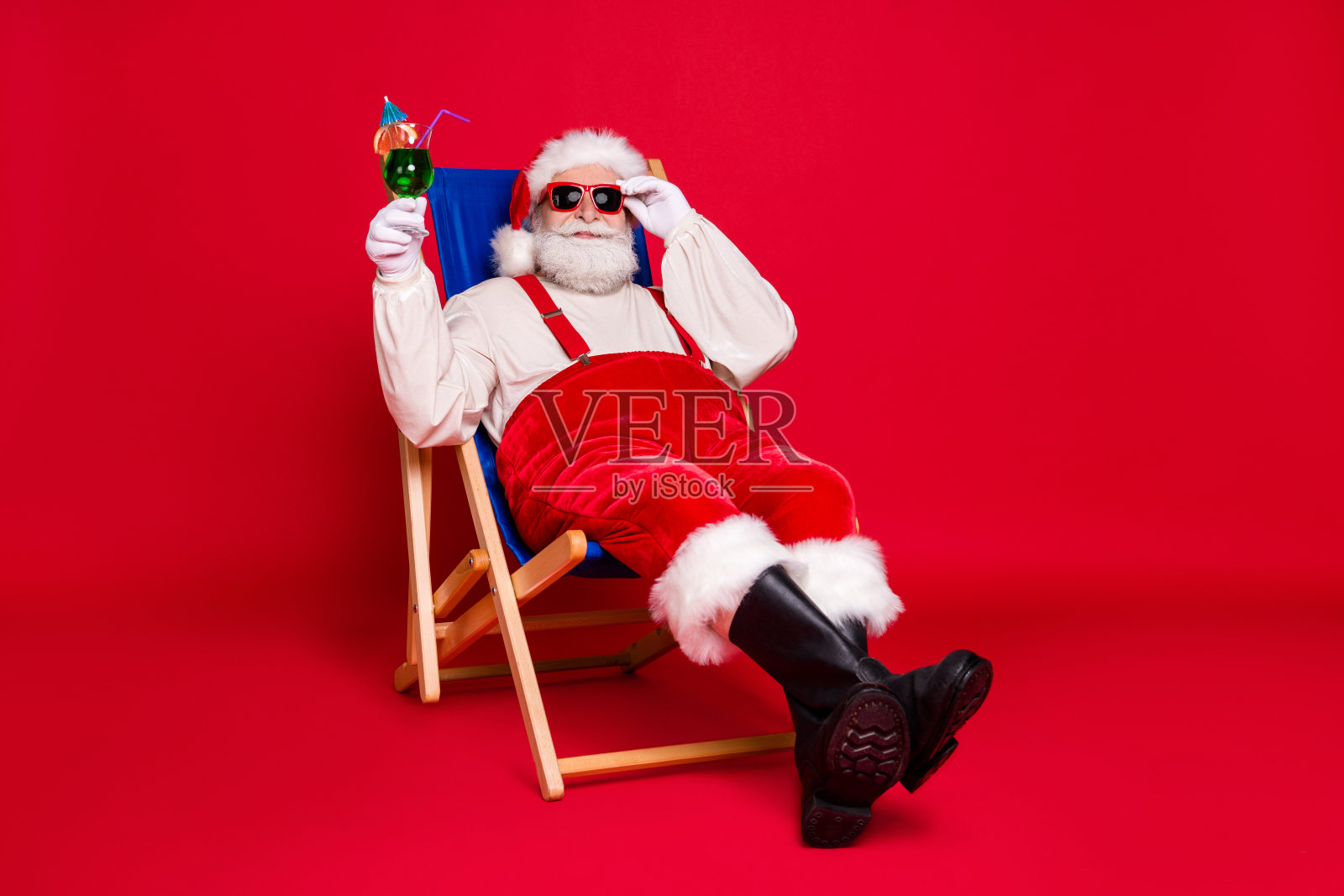 他的肖像他漂亮的英俊愉快的长胡子的胖圣诞老人，嬉皮士的家伙坐在椅子上放松，放松，放松，度过周末，休闲孤立的明亮，生动的闪耀，充满活力的红色背景照片摄影图片
