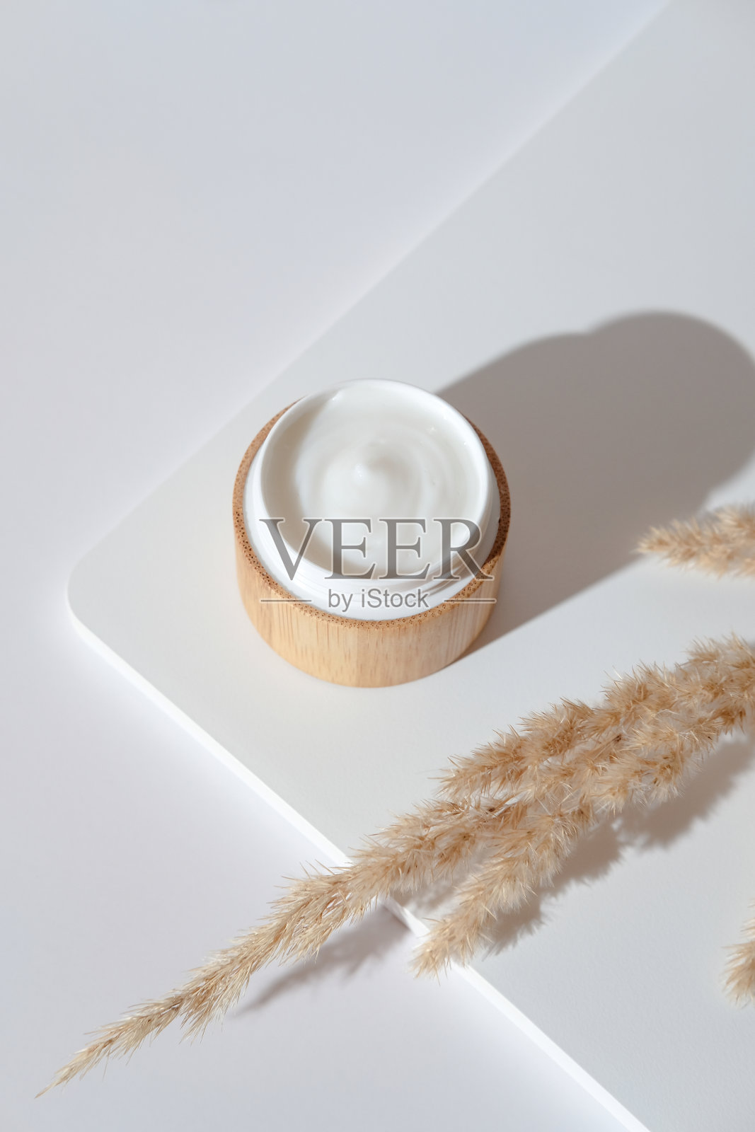 天然有机保湿霜，环保竹瓶和干花在白色讲台。生态化妆品，素食美容产品照片摄影图片