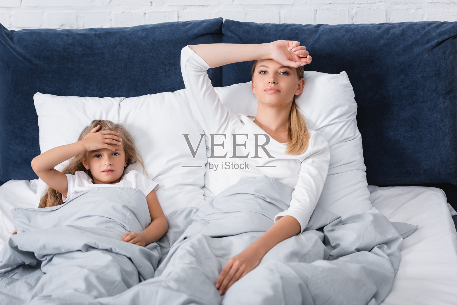 选择性聚焦的病母亲看着相机附近的孩子在床上照片摄影图片