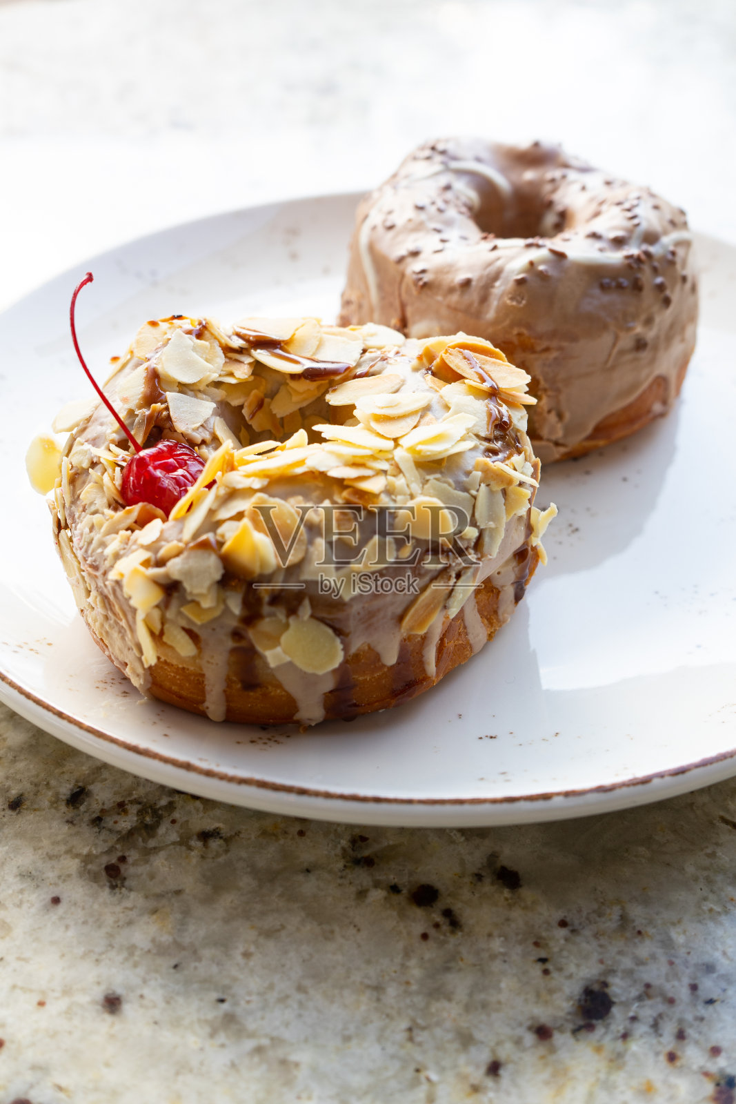 大理石桌子上的盘子里放着甜甜圈。照片摄影图片