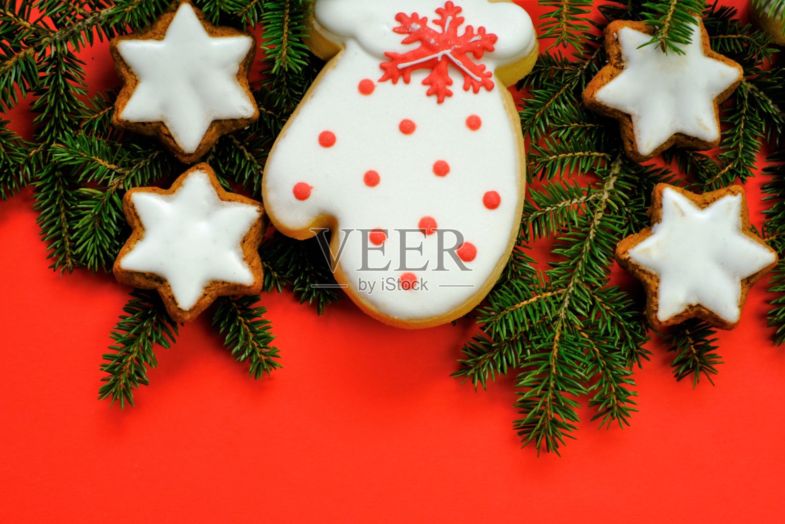 圣诞节和新年的概念。圣诞姜饼和饼干。寒假糖果。红色背景上有星星和冷杉树枝的姜饼照片摄影图片
